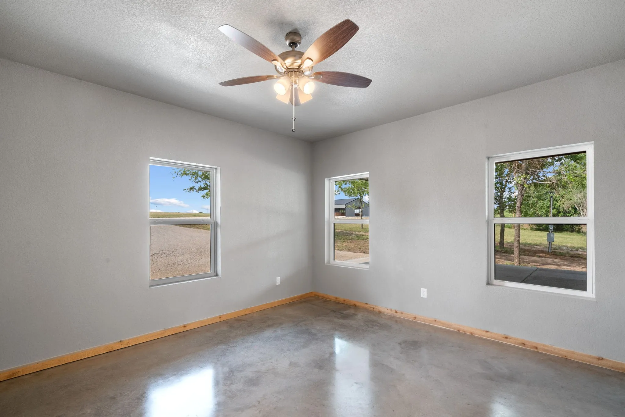 Empty room with ceiling fan, concrete flooring, and a textured ceiling