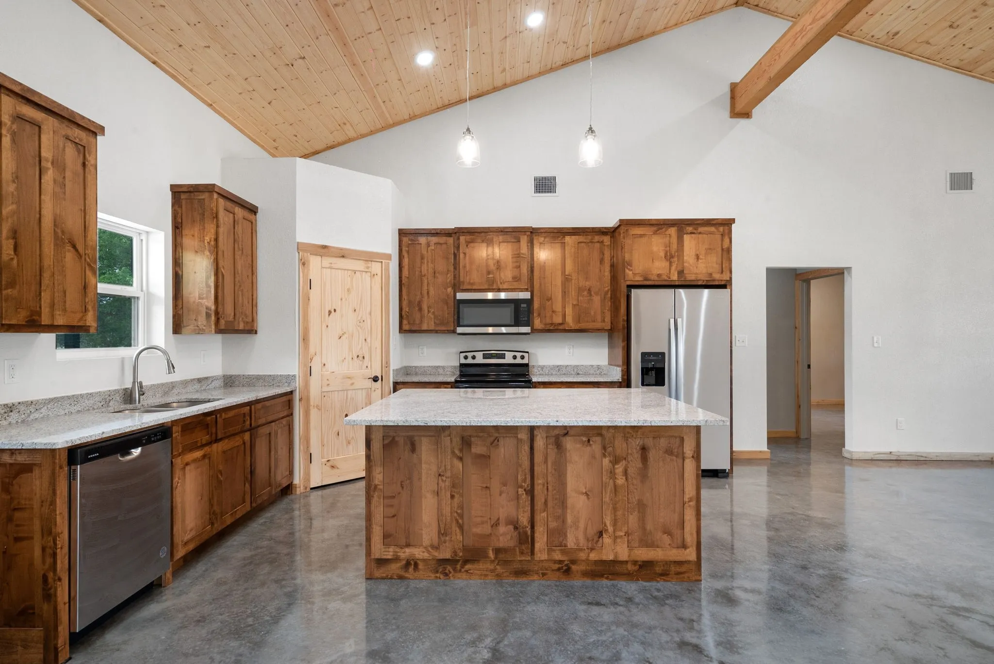 Kitchen with decorative light fixtures, a kitchen island, high vaulted ceiling, appliances with stainless steel finishes, and sink