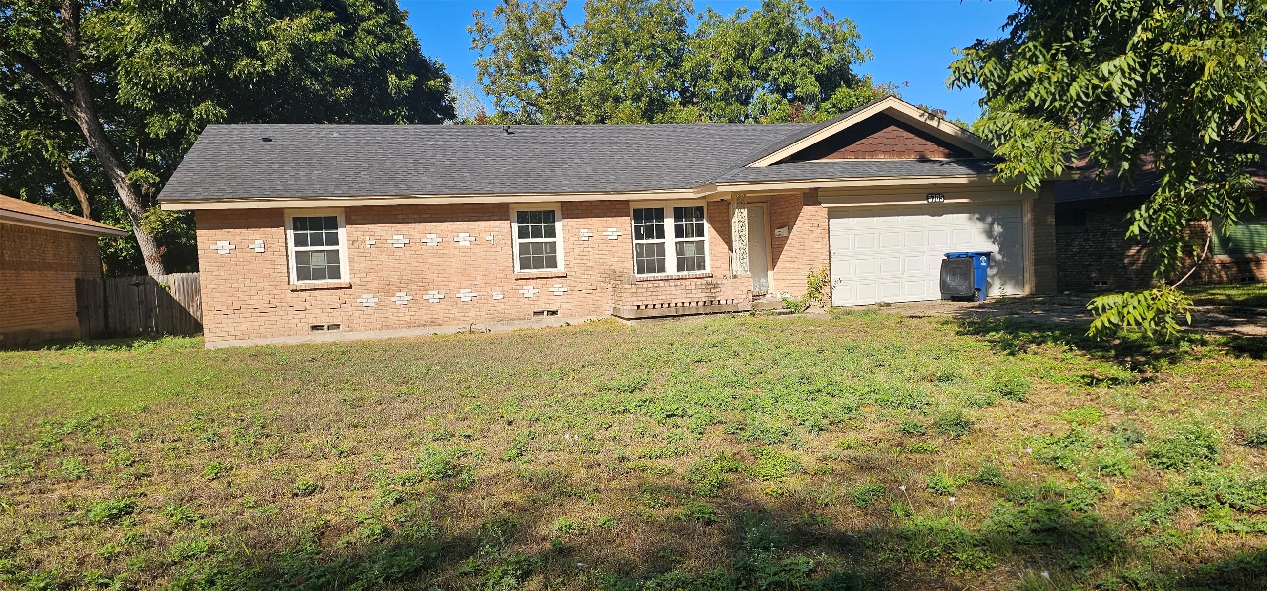 Brick exterior with decorative accents, attached garage, gabled roofline, and multiple windows