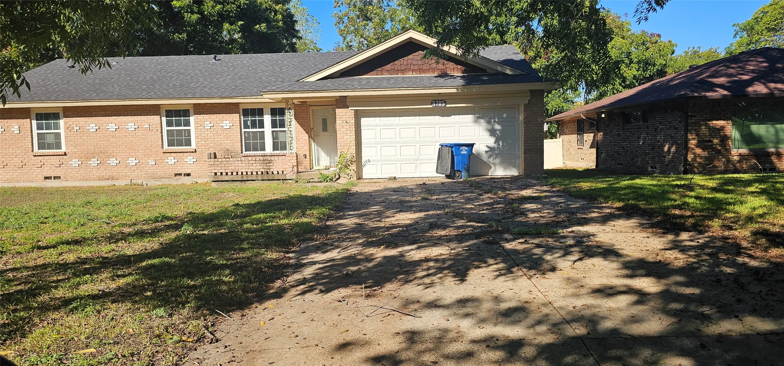 Brick exterior with an attached garage, featuring a shingle roof and multiple windows