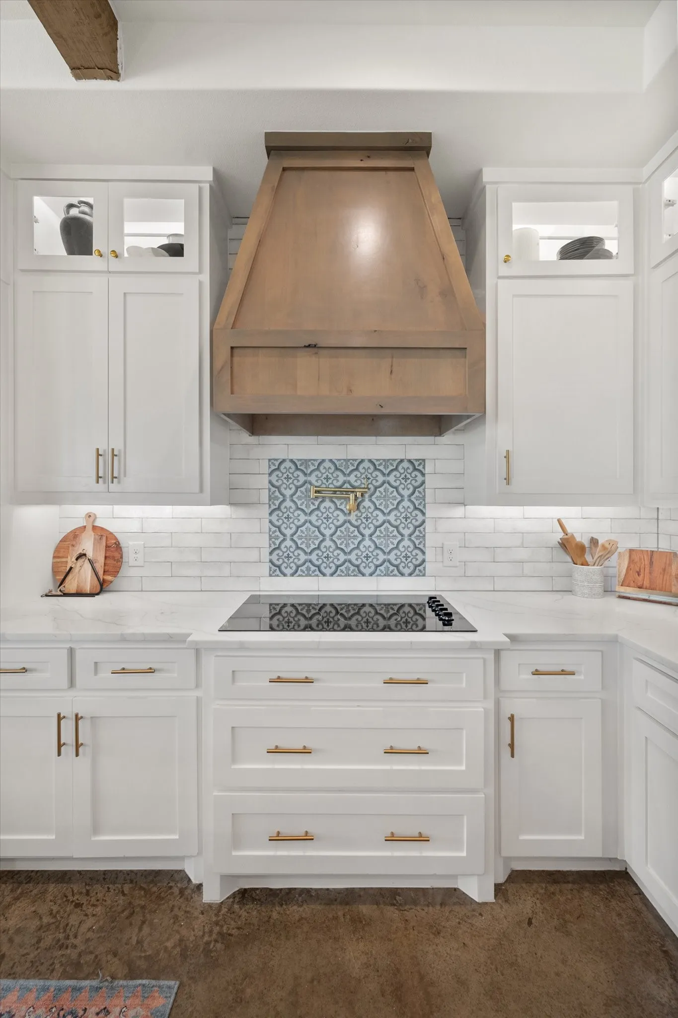 Kitchen with white cabinetry, pot filler, premium range hood, backsplash, and black electric stovetop