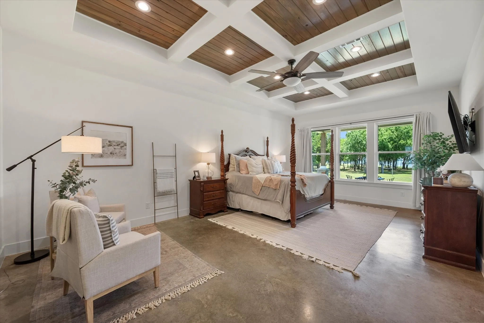 Primary Bedroom with wood beamed ceiling, coffered ceiling, ceiling fan, and concrete flooring