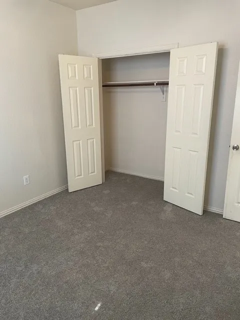 Unfurnished bedroom with a closet and dark carpet