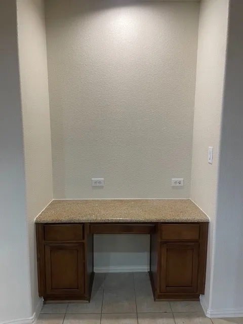Unfurnished office with built in desk and light tile flooring
