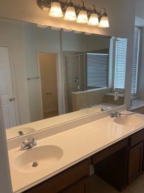 Bathroom featuring separate shower and tub and double sink vanity