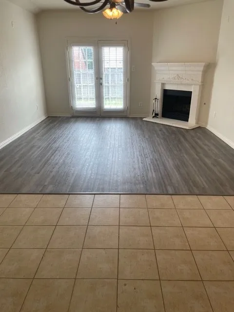 Unfurnished living room featuring a fireplace, ceiling fan, and dark wood-type flooring