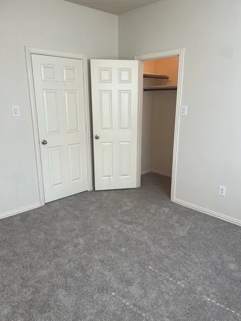 Unfurnished bedroom featuring dark carpet and a closet