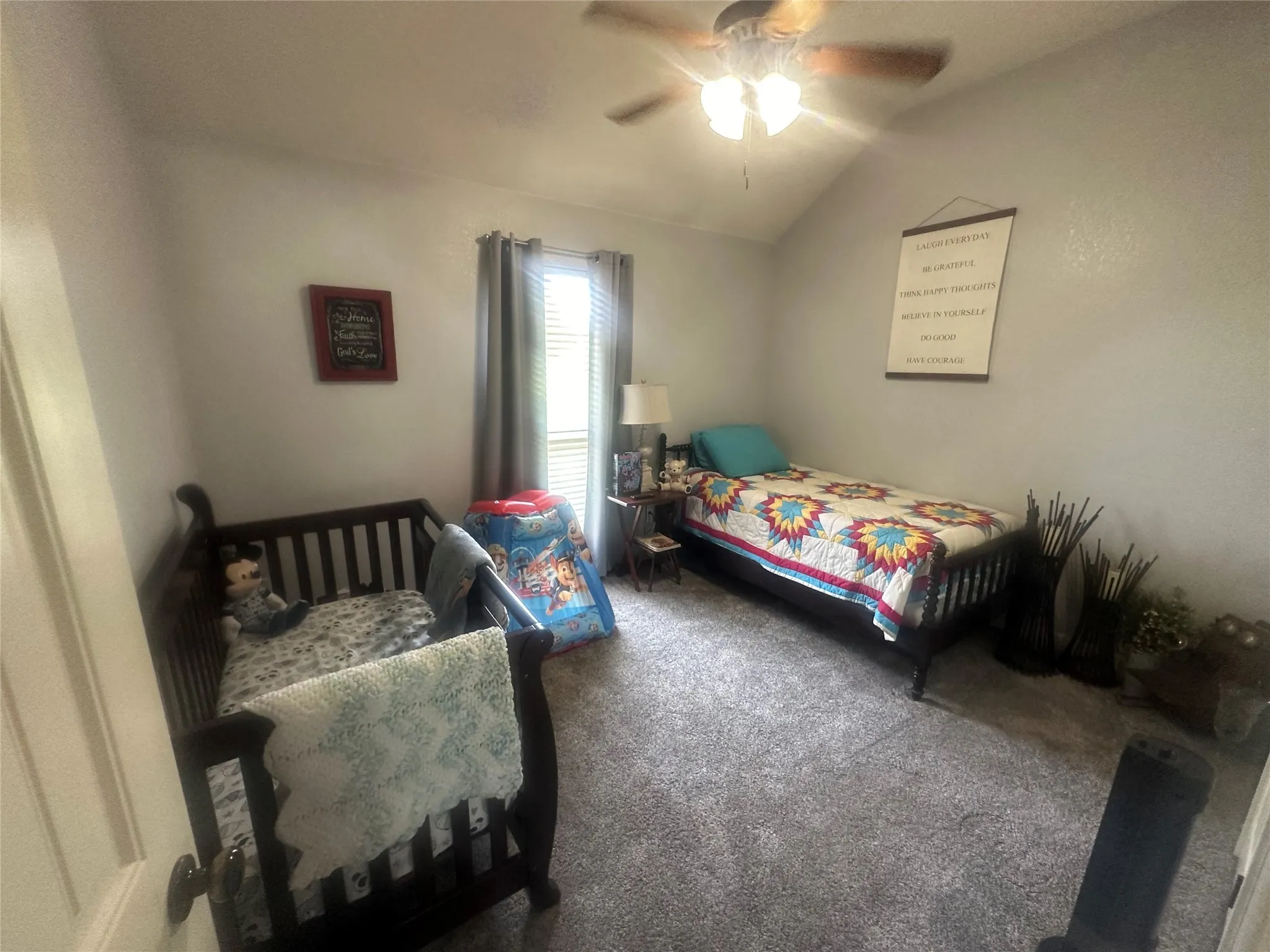 Carpeted bedroom featuring ceiling fan and lofted ceiling
