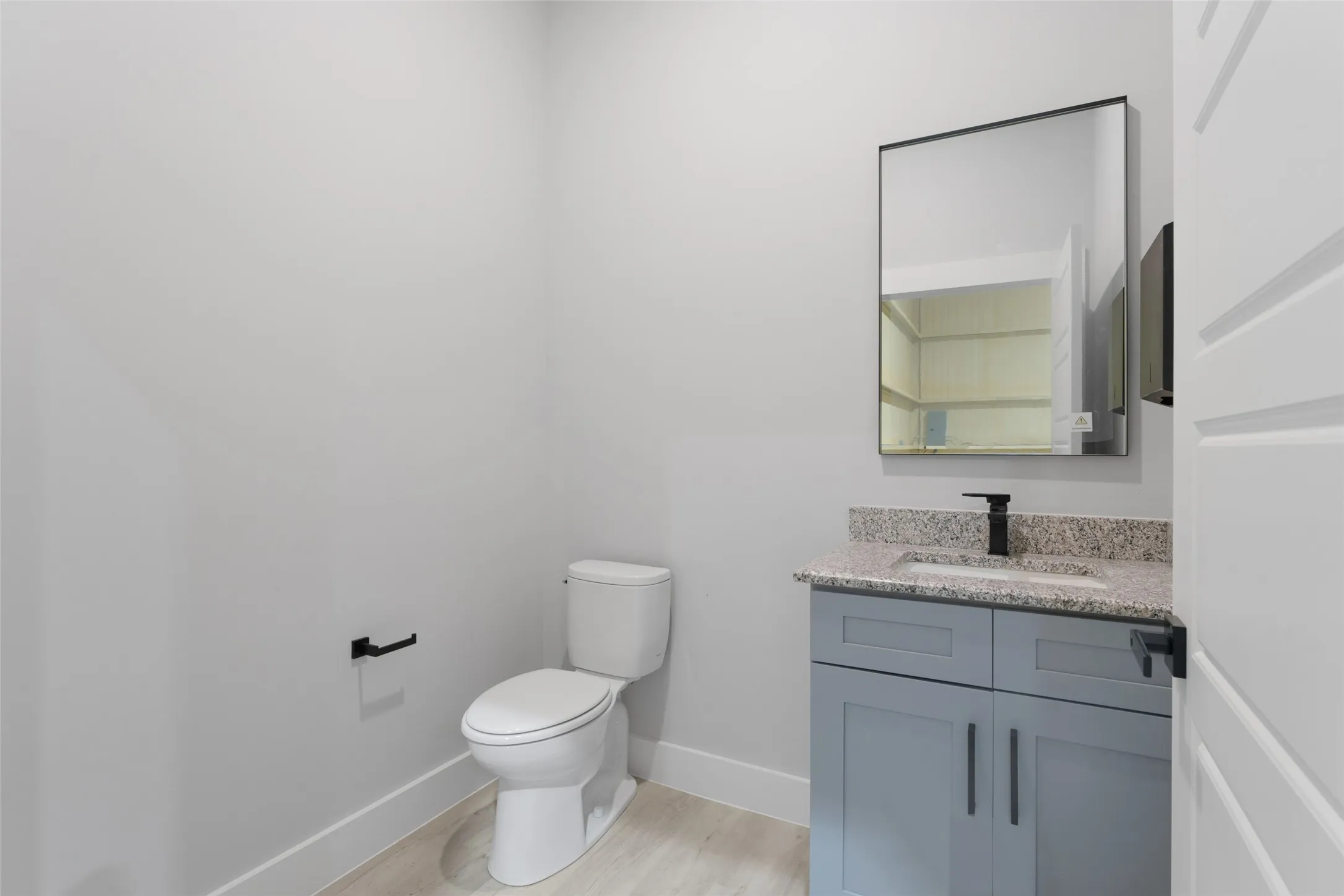 Bathroom featuring hardwood / wood-style floors, toilet, and vanity