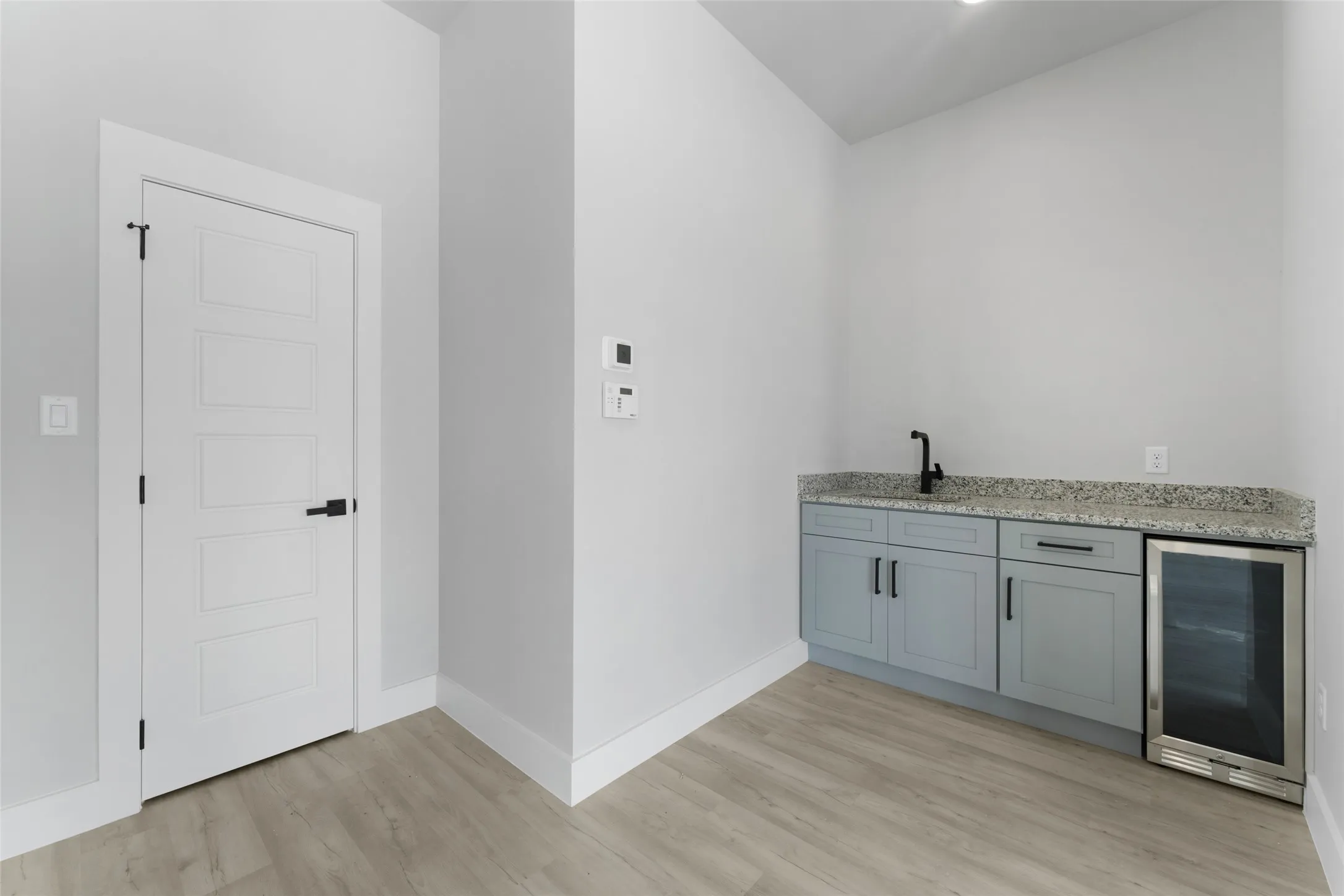 Bar featuring beverage cooler, light hardwood / wood-style floors, light stone counters, and sink
