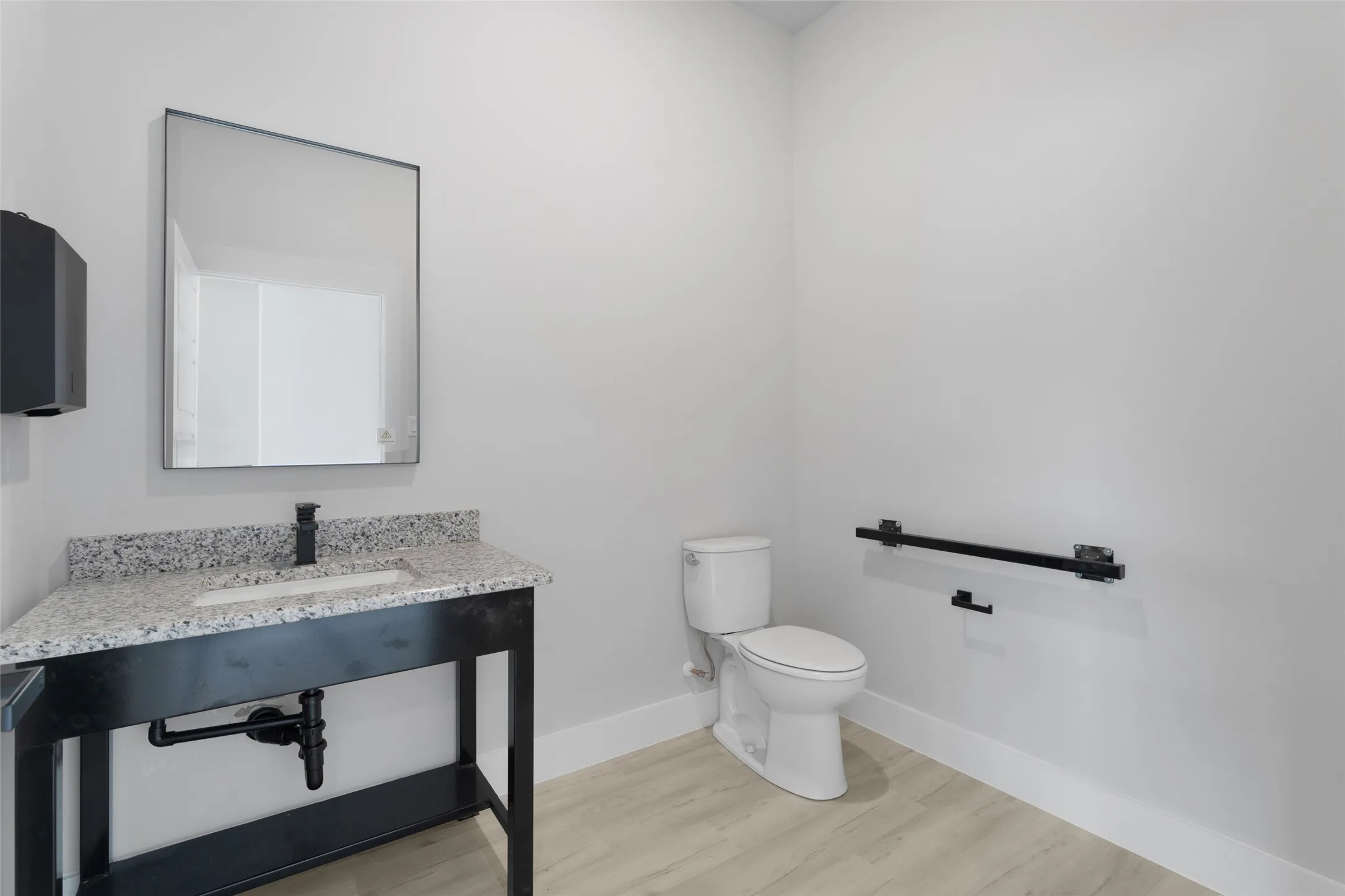 Bathroom featuring wood-type flooring, toilet, and vanity