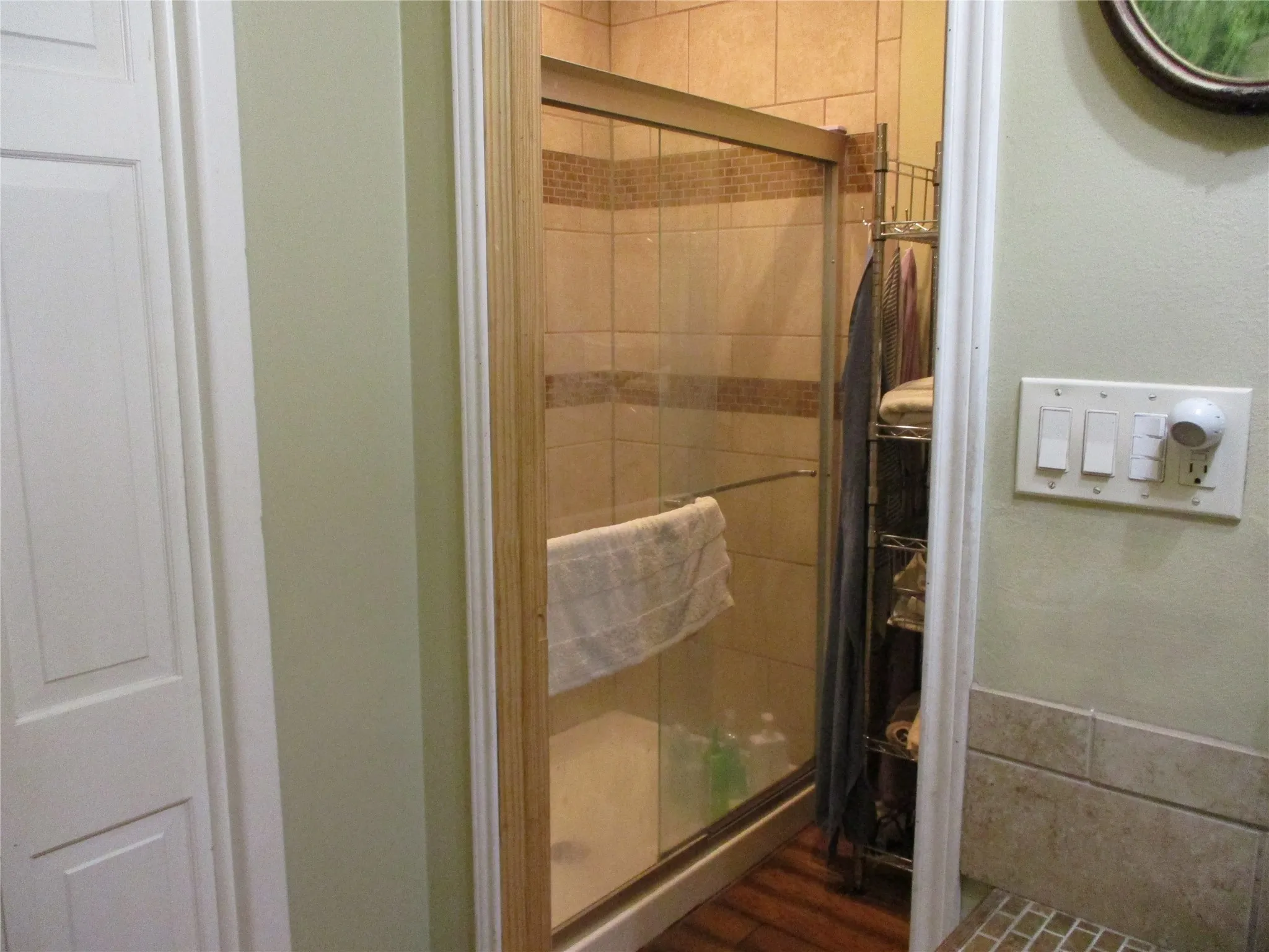 Bathroom featuring a shower with shower door and wood-type flooring