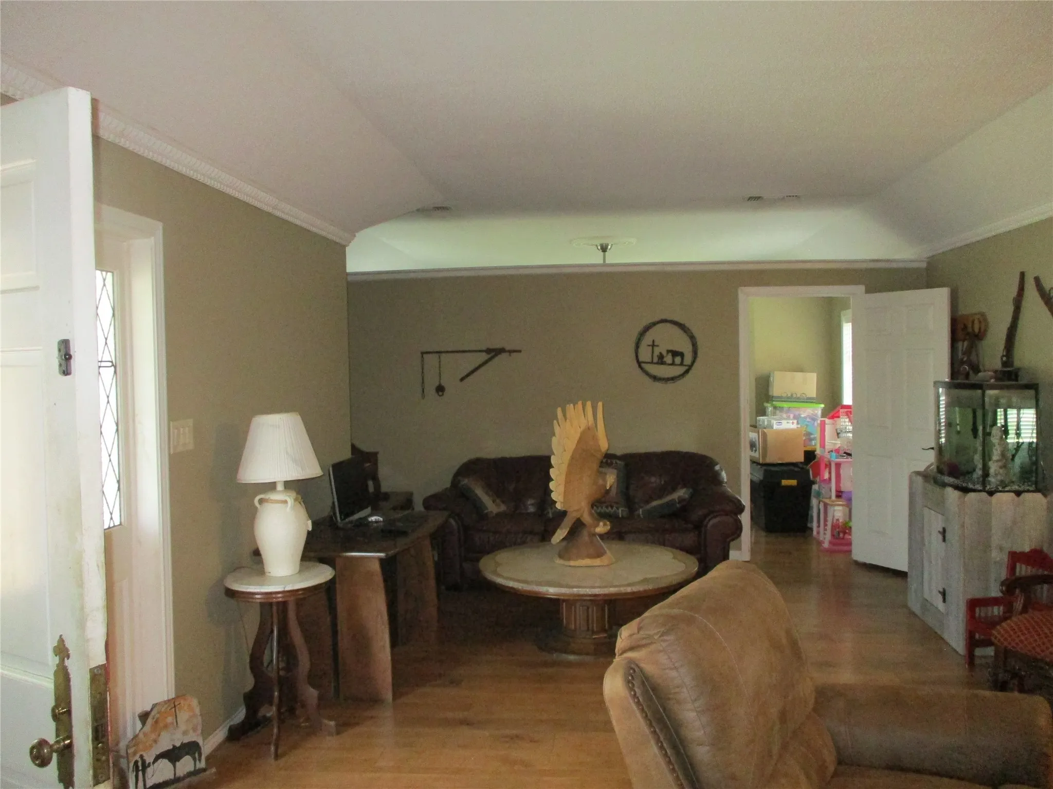 Living room featuring wood-type flooring, lofted ceiling, and crown molding