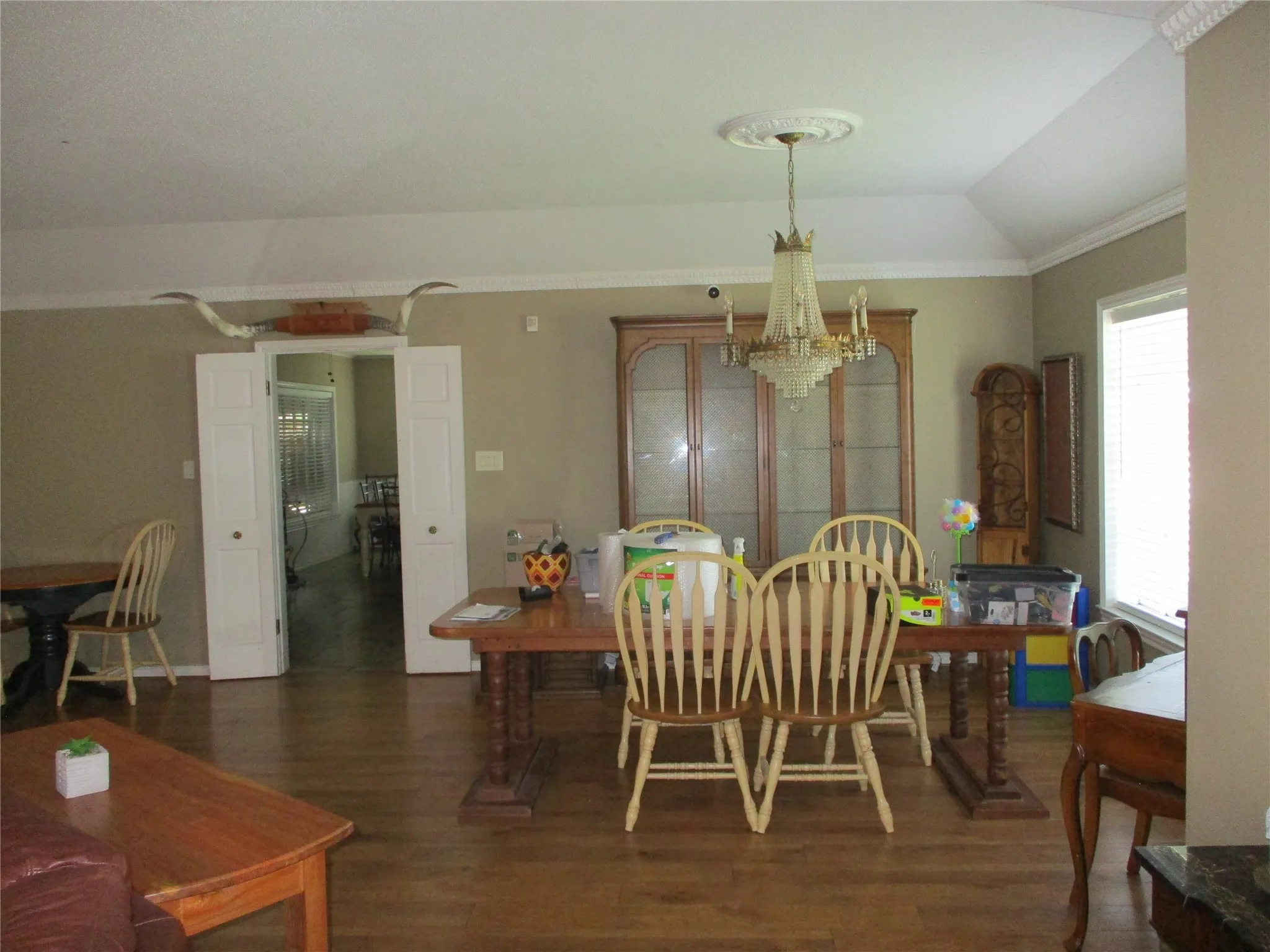 Dining area featuring dark hardwood / wood-style floors, crown molding, vaulted ceiling, and a chandelier