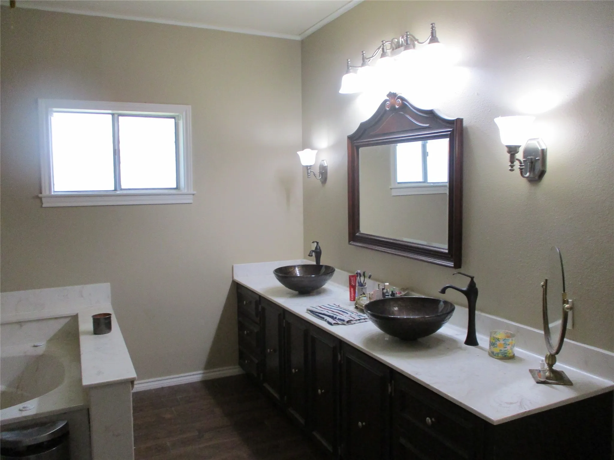 Bathroom featuring a healthy amount of sunlight, wood-type flooring, double sink vanity, and crown molding