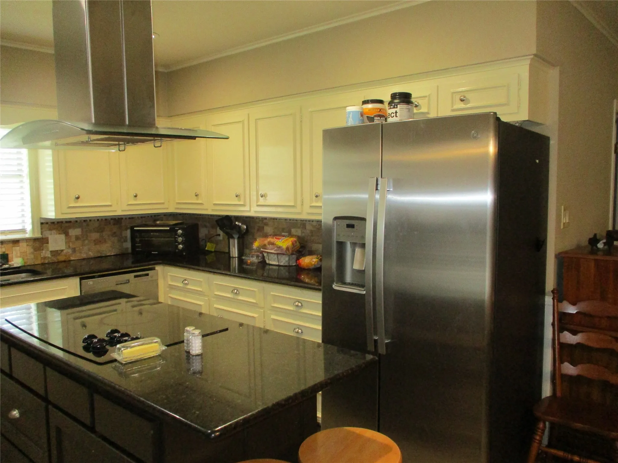 Kitchen featuring stainless steel fridge with ice dispenser, white cabinetry, white dishwasher, decorative backsplash, and island range hood