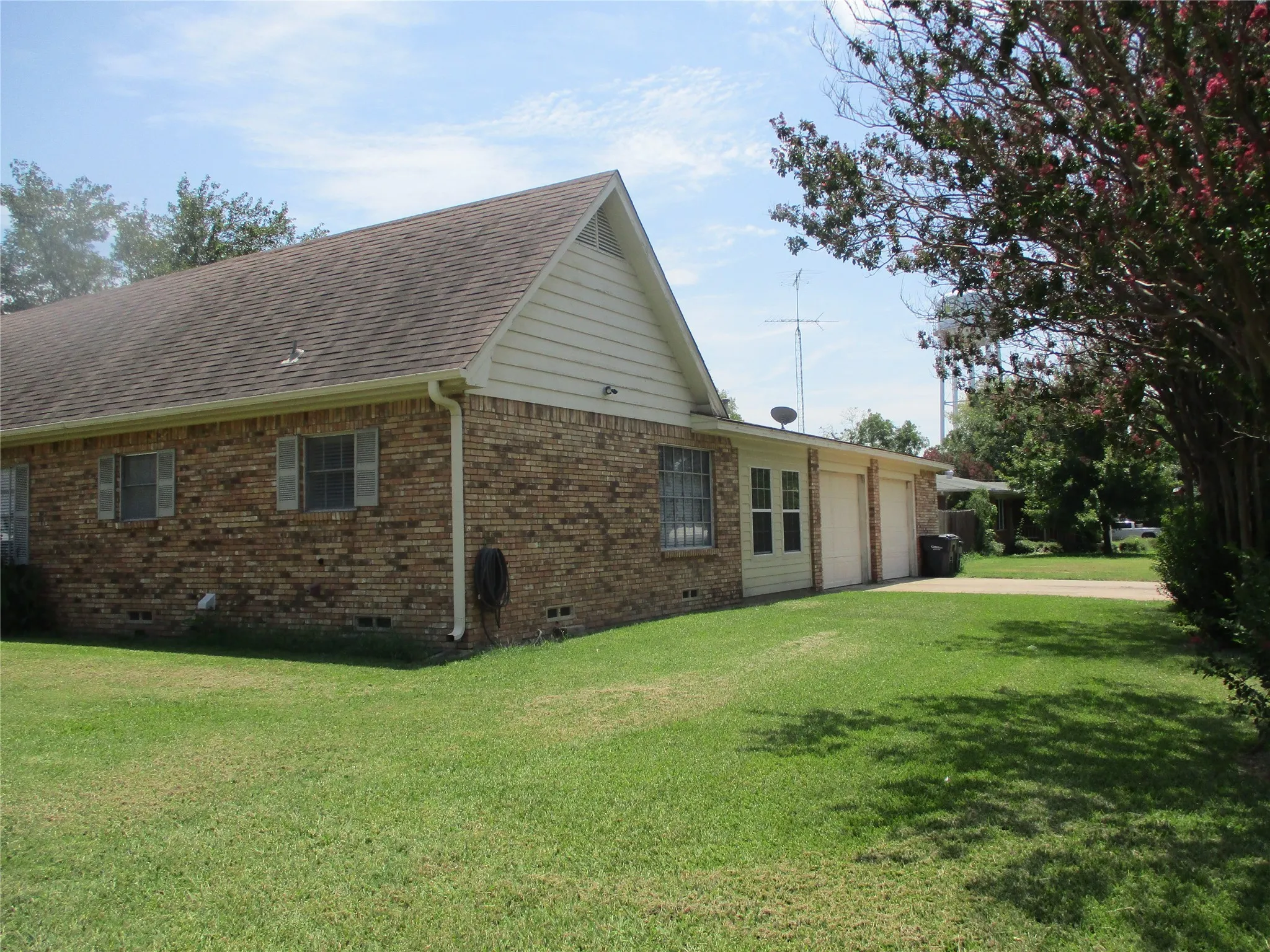 View of side of home featuring a garage and a yard