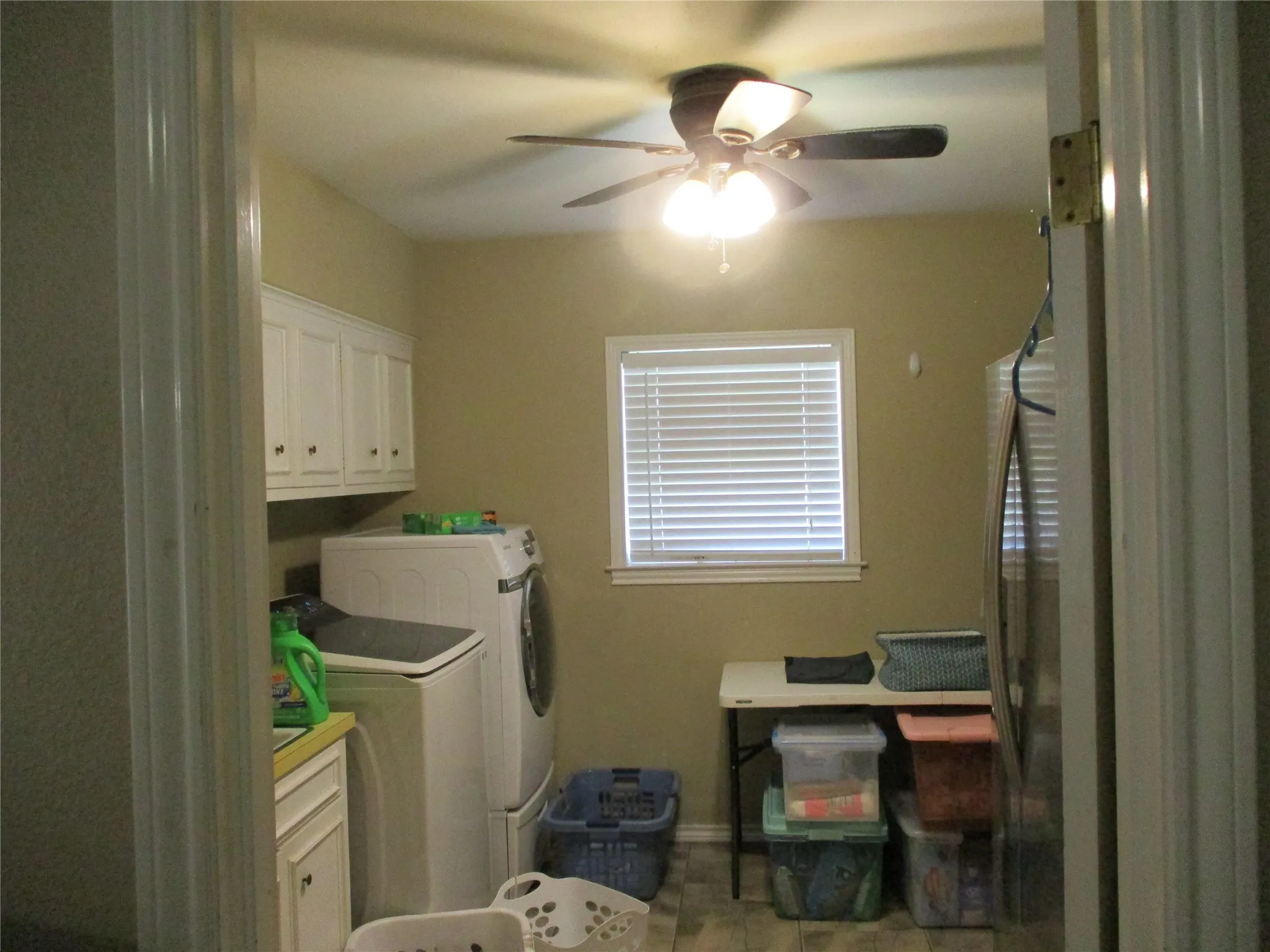 Laundry area with tile patterned floors, washer and clothes dryer, cabinets, and ceiling fan
