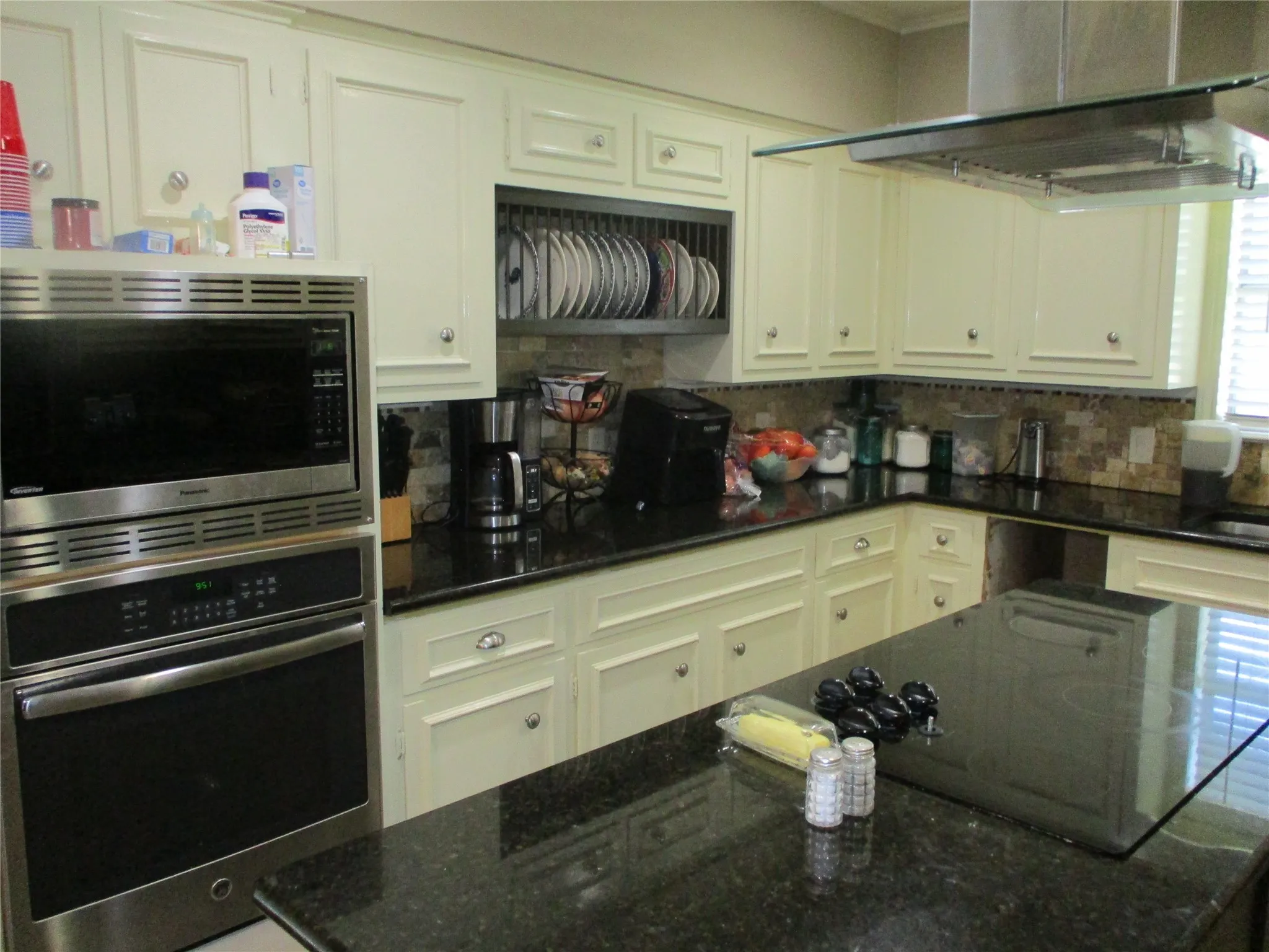 Kitchen with dark stone countertops, decorative backsplash, appliances with stainless steel finishes, and white cabinets