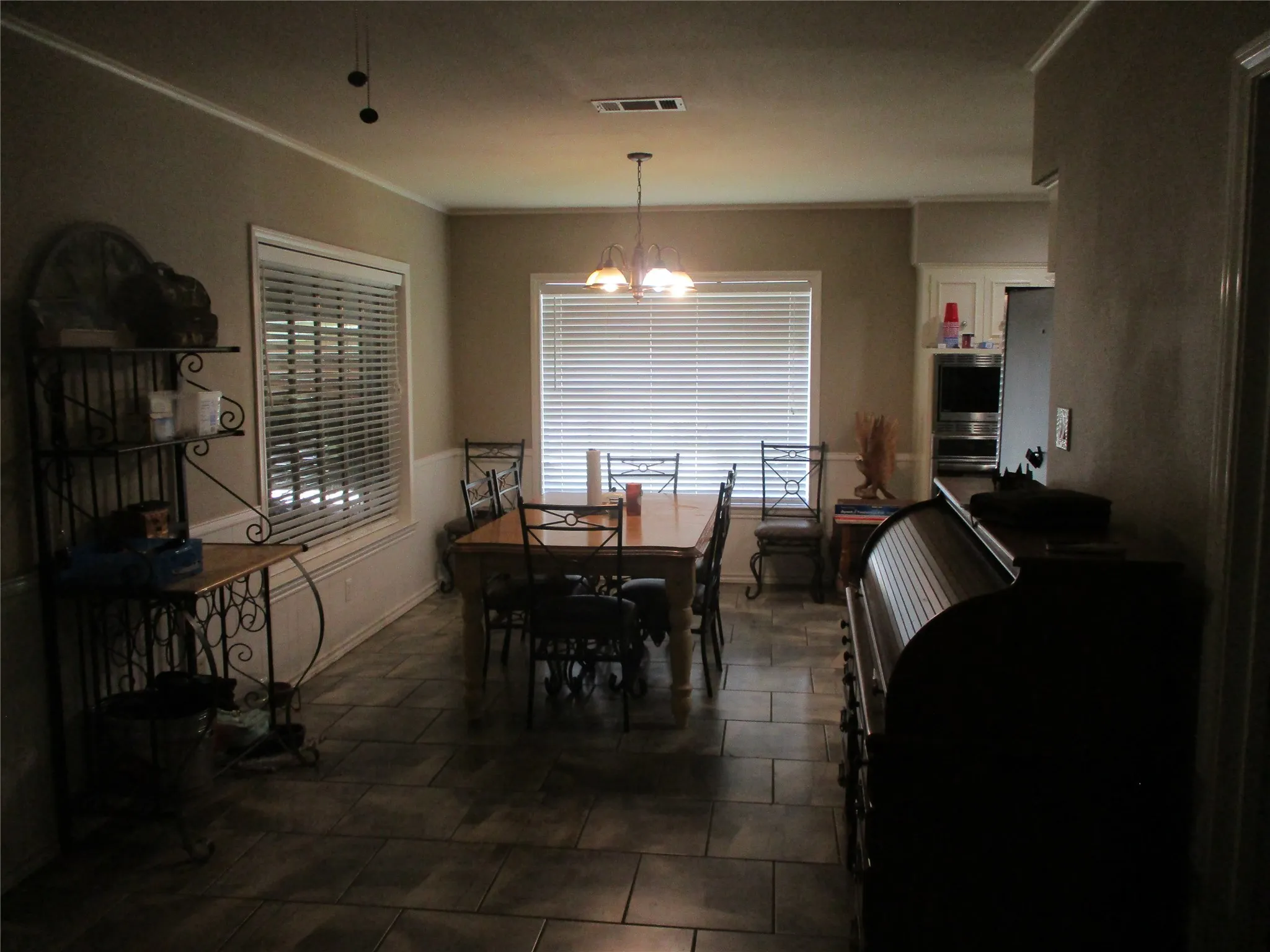 Dining room featuring crown molding, dark tile patterned flooring, and a notable chandelier