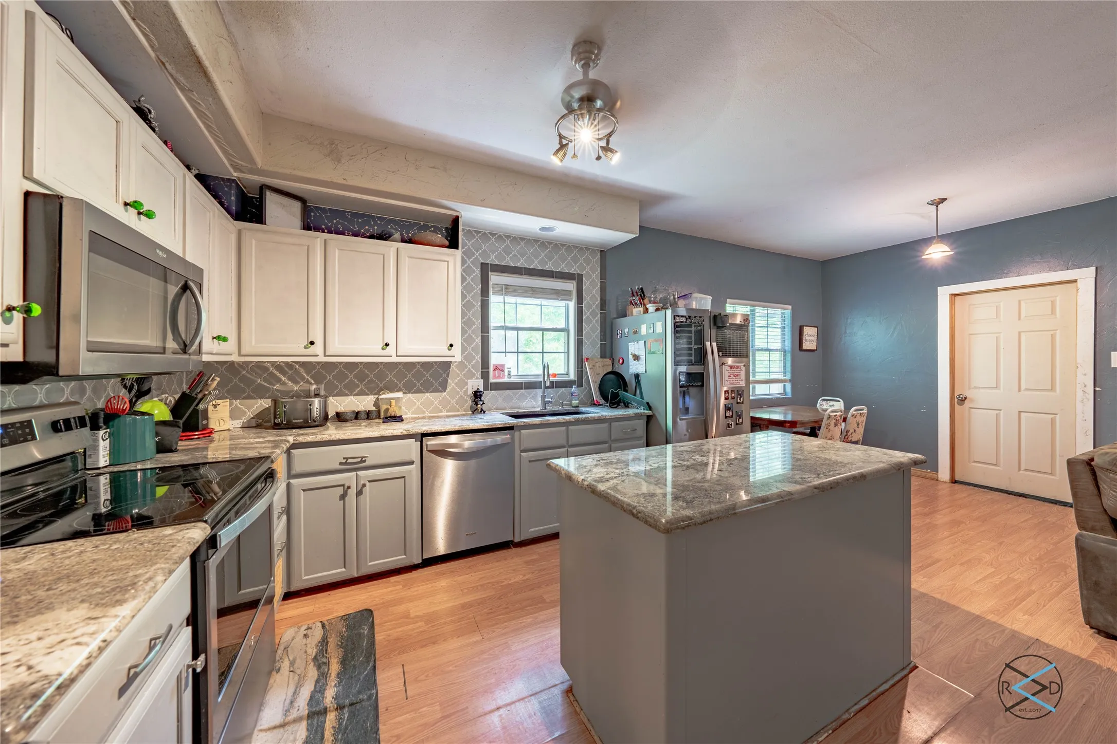 Kitchen with a center island, appliances with stainless steel finishes, decorative backsplash, and light hardwood / wood-style floors