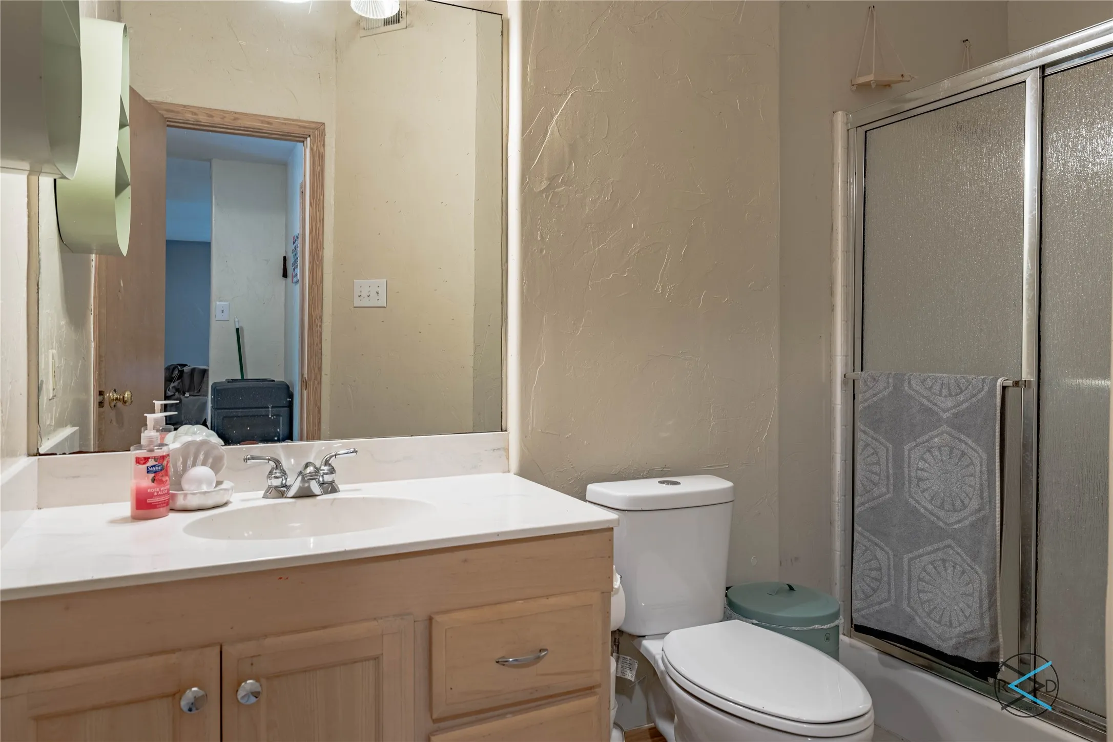 Full bathroom featuring toilet, vanity, and enclosed tub / shower combo