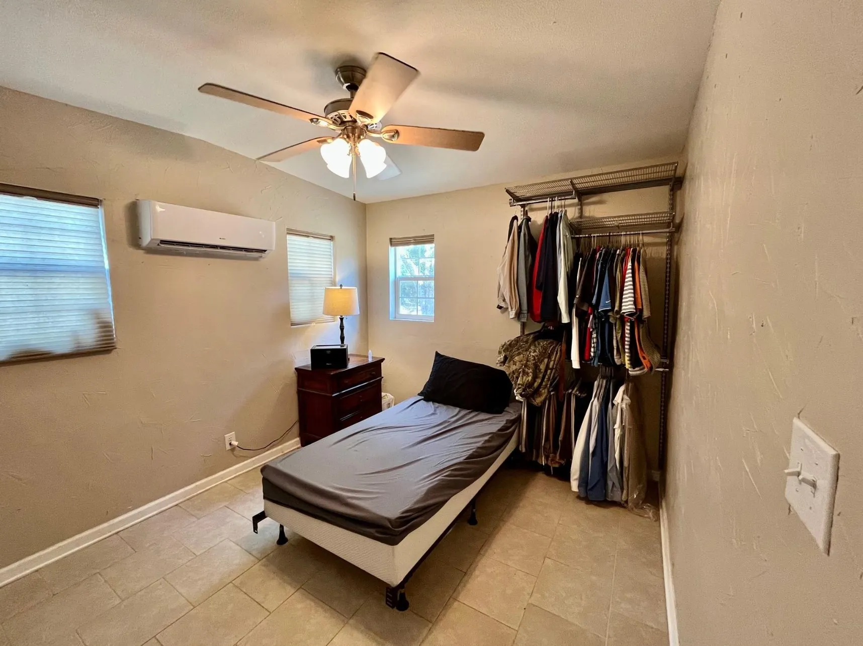 Tiled bedroom featuring a wall mounted AC and ceiling fan