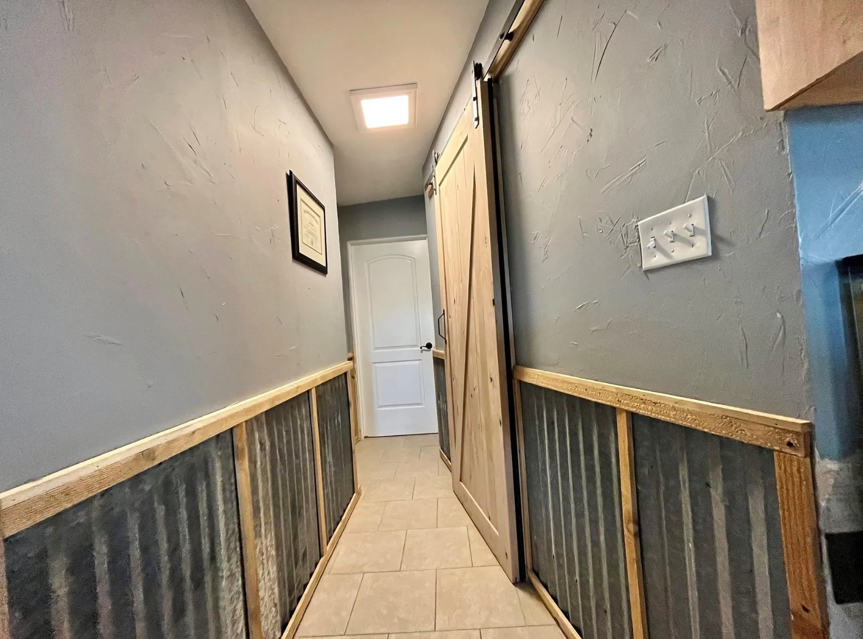 Corridor featuring a barn door and light tile patterned floors