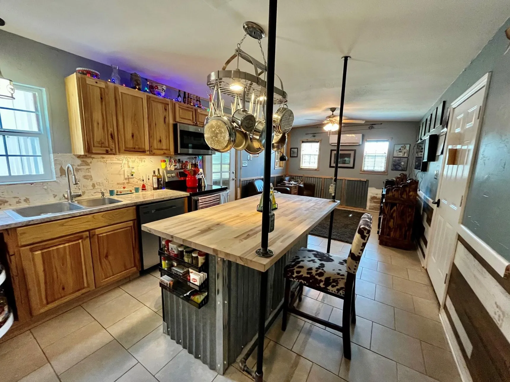 Kitchen with butcher block counters, ceiling fan with notable chandelier, sink, a kitchen island, and appliances with stainless steel finishes