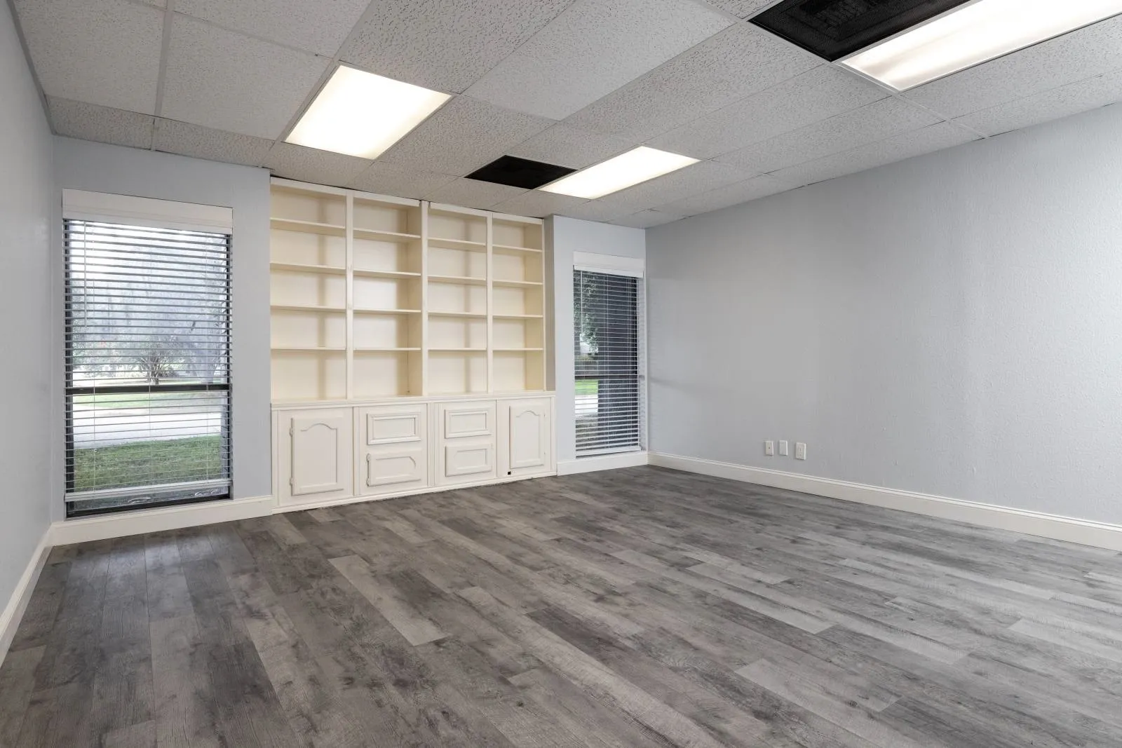 Unfurnished living room with built in shelves, hardwood / wood-style flooring, and a paneled ceiling