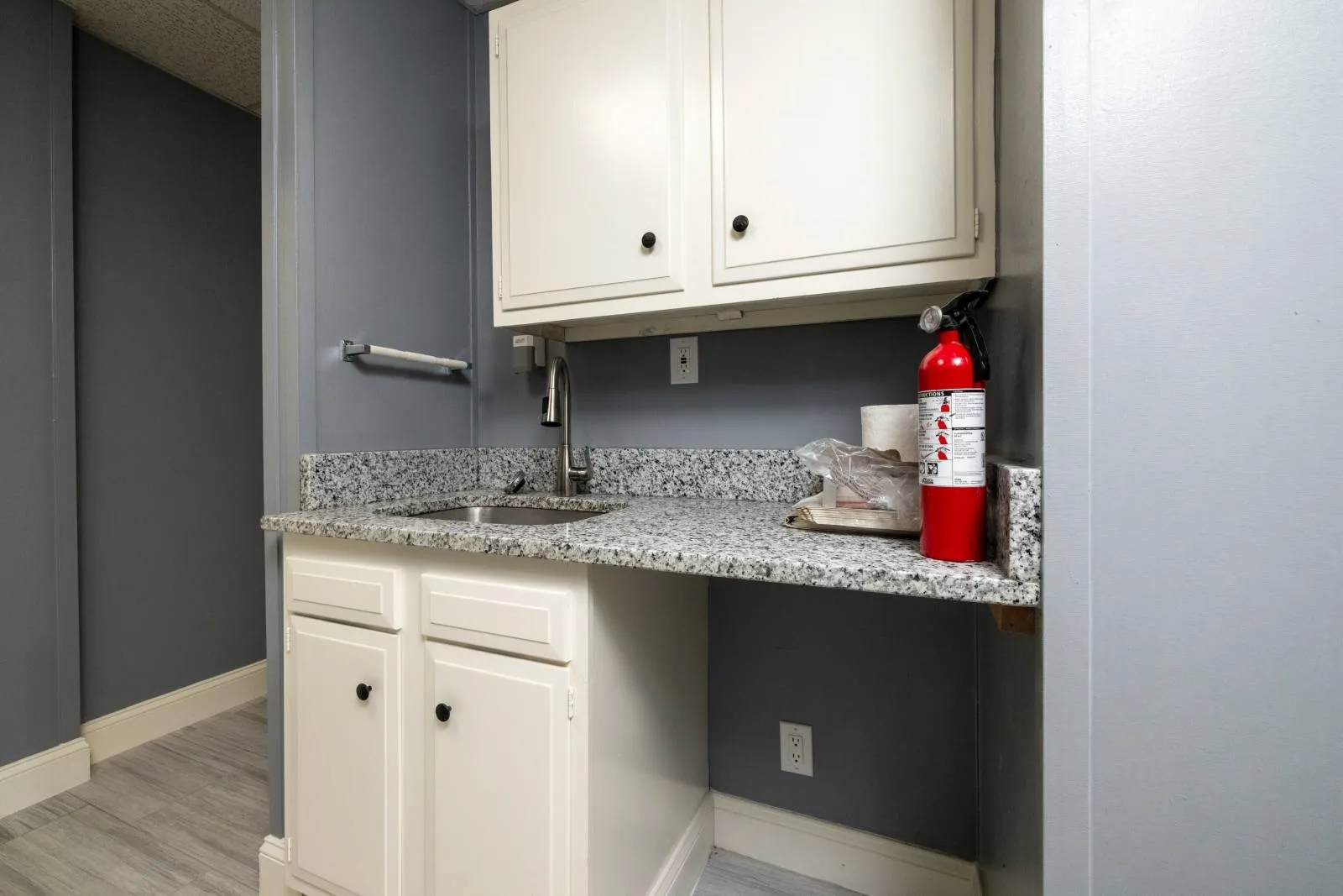 Kitchen with sink, white cabinetry, light stone counters, and light hardwood / wood-style flooring