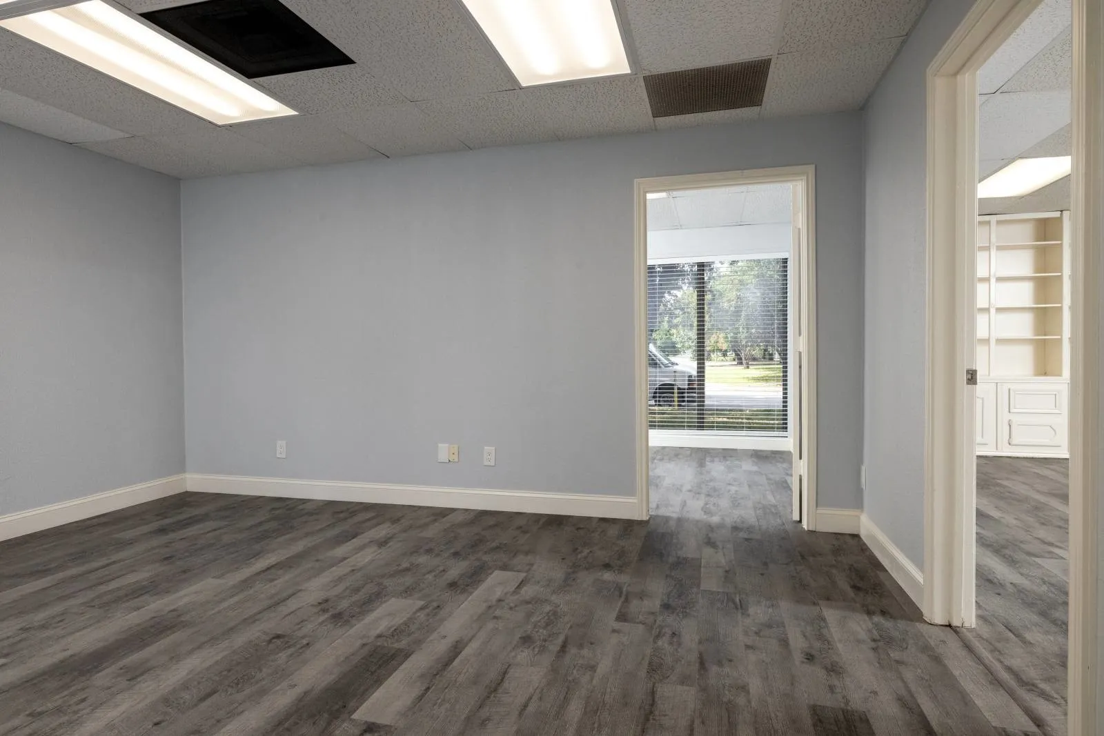 Unfurnished room featuring built in features, a paneled ceiling, and hardwood / wood-style floors