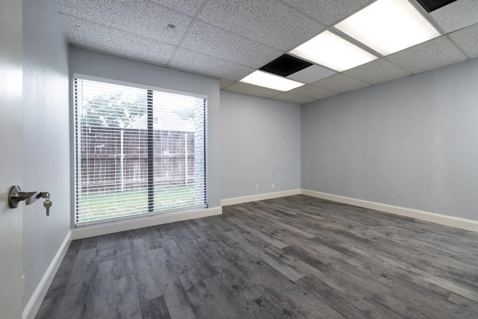 Empty room with hardwood / wood-style flooring and a drop ceiling