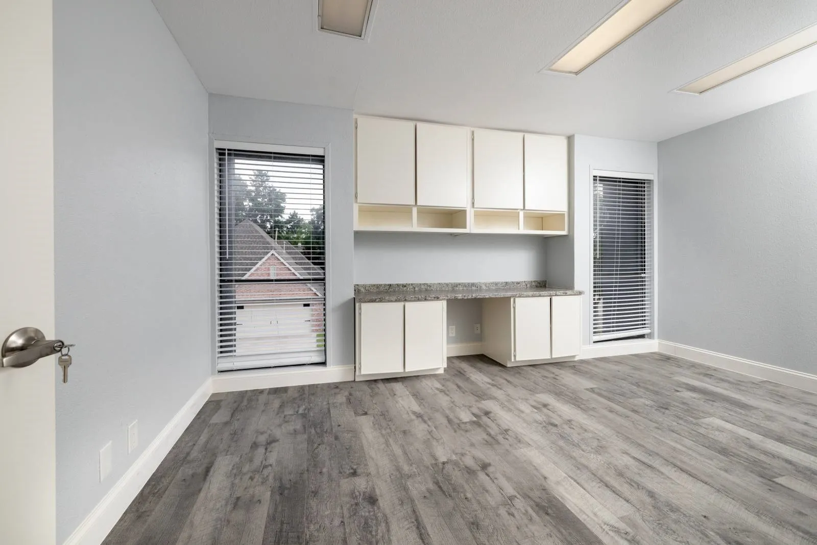 Unfurnished living room featuring built in desk and light hardwood / wood-style floors