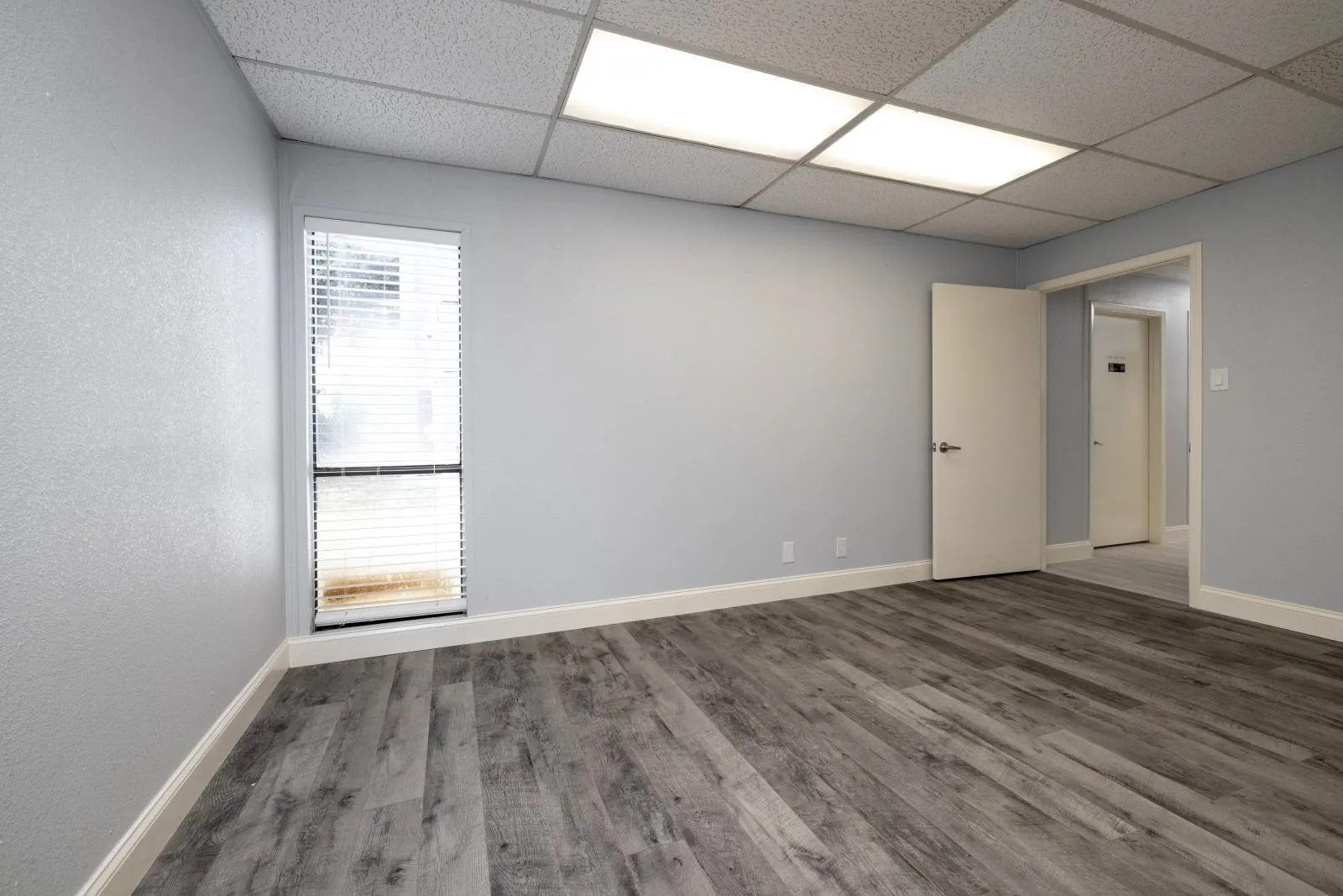 Empty room featuring a healthy amount of sunlight, hardwood / wood-style flooring, and a drop ceiling