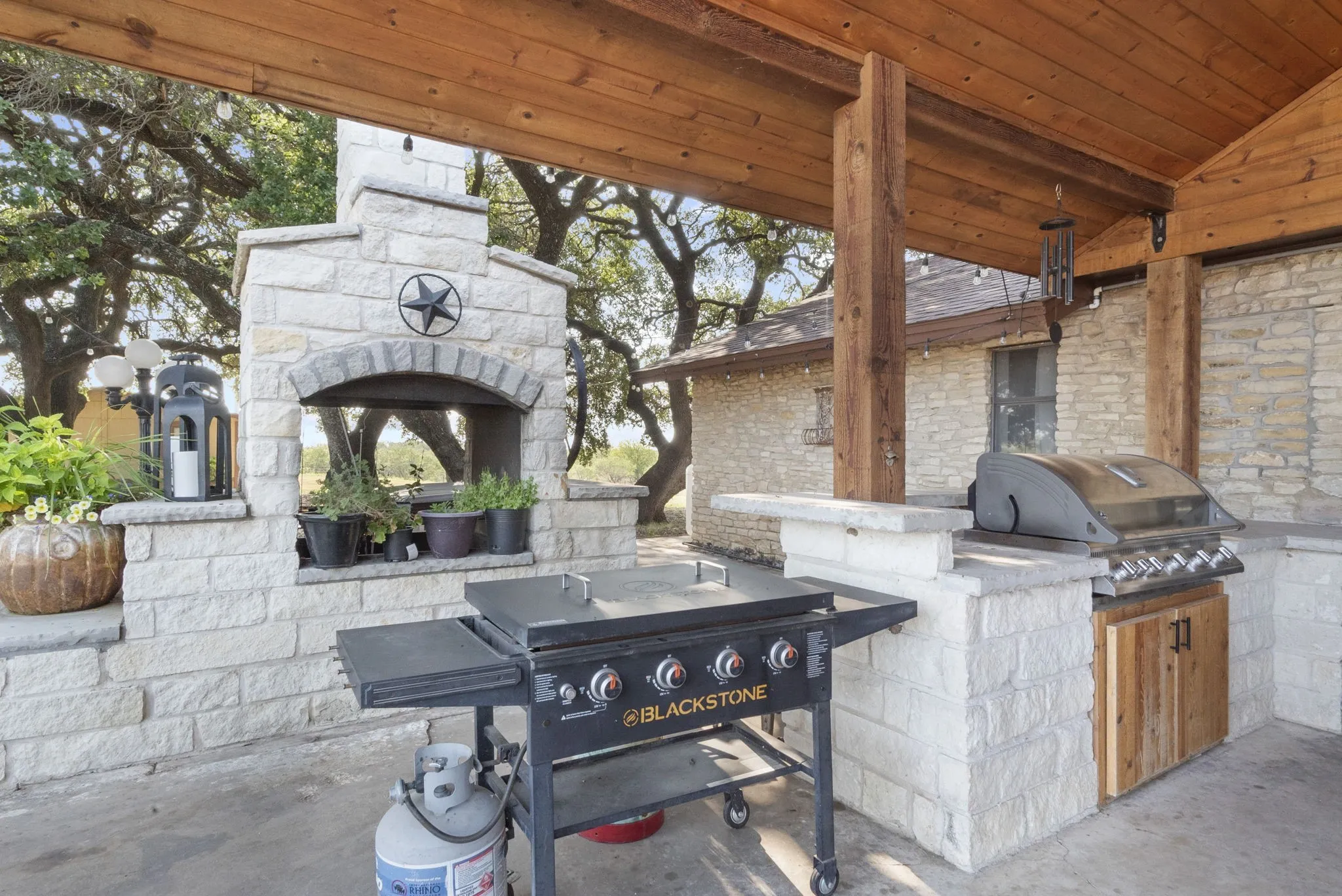 View of patio with exterior kitchen, an outdoor stone fireplace, and area for grilling