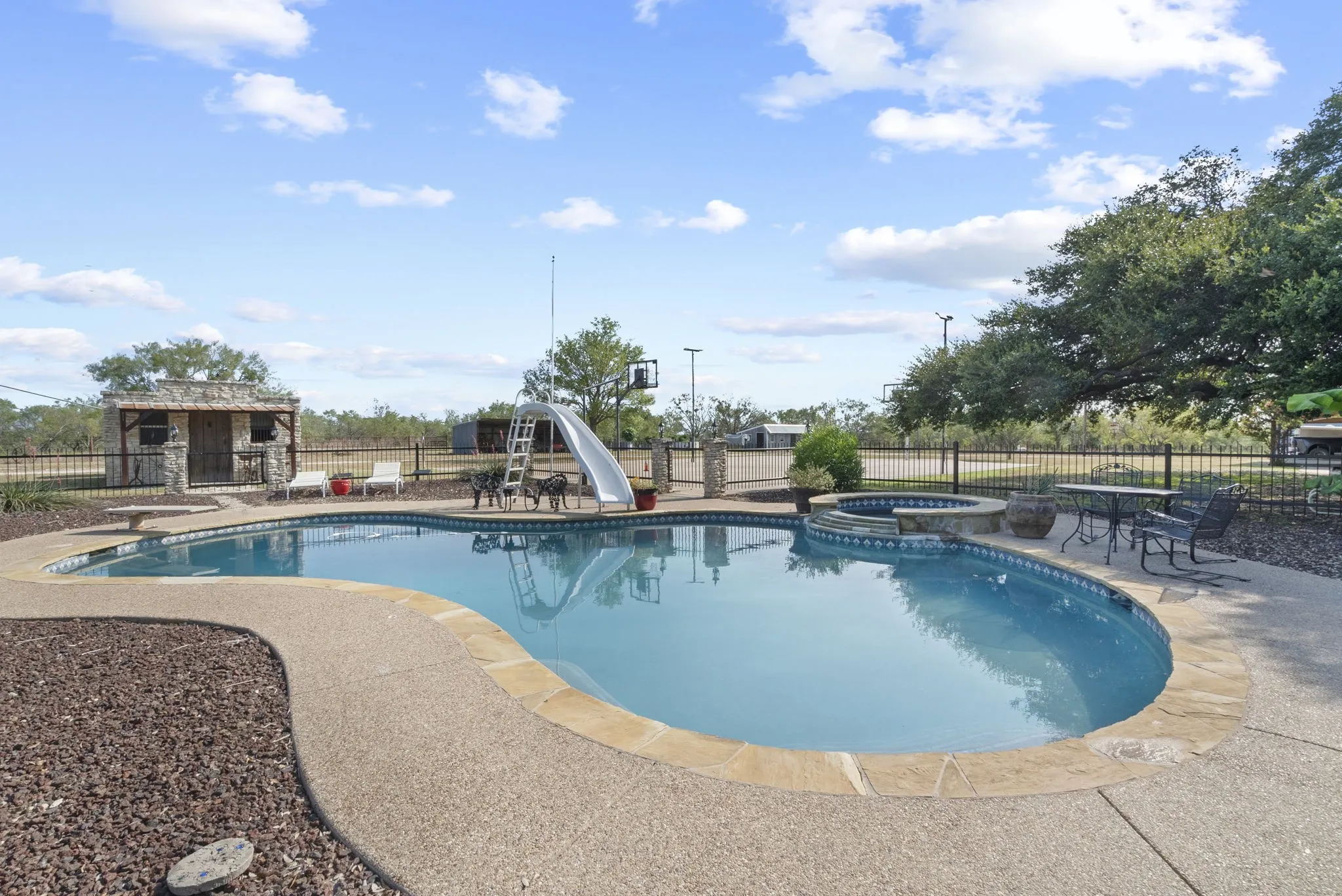View of pool with a water slide, a patio, and an in ground hot tub