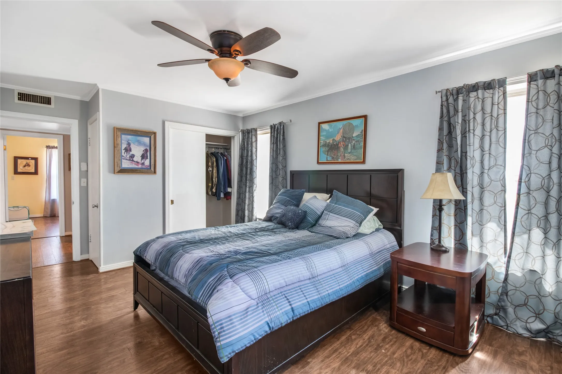 Bedroom with ceiling fan, dark hardwood / wood-style floors, and multiple windows