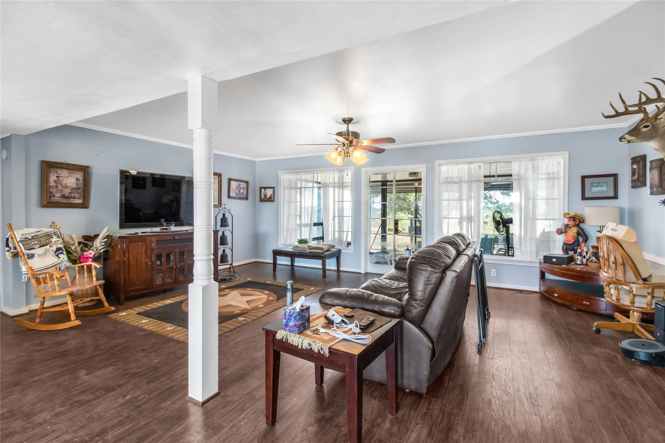 Living room featuring decorative columns, ceiling fan, hardwood / wood-style floors, and crown molding