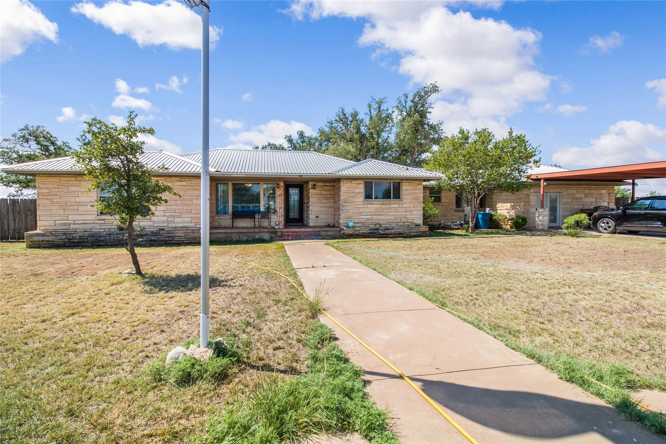 Ranch-style house featuring a front lawn and a carport