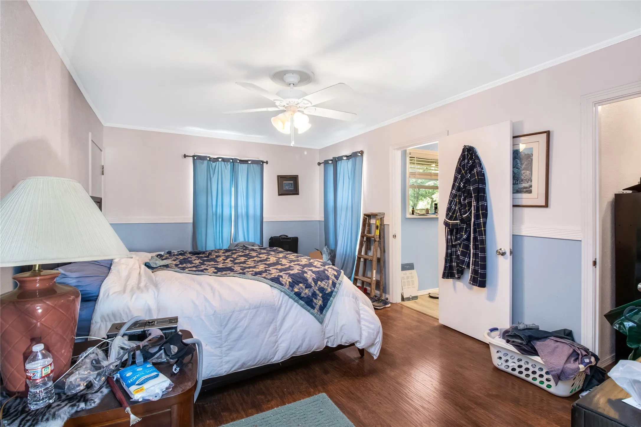 Bedroom with ceiling fan, wood-type flooring, and ornamental molding
