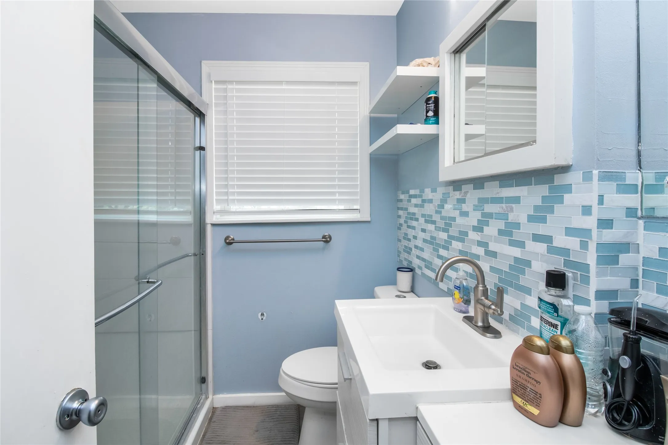 Bathroom featuring decorative backsplash, walk in shower, vanity, and toilet