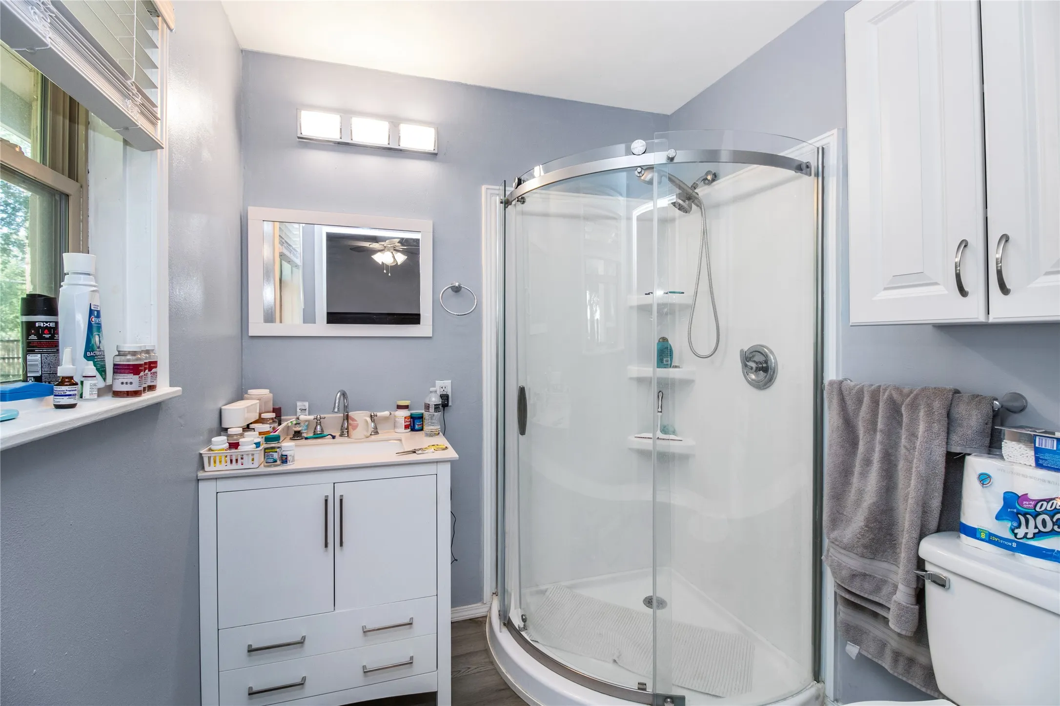 Bathroom with an enclosed shower, vanity, toilet, and hardwood / wood-style floors