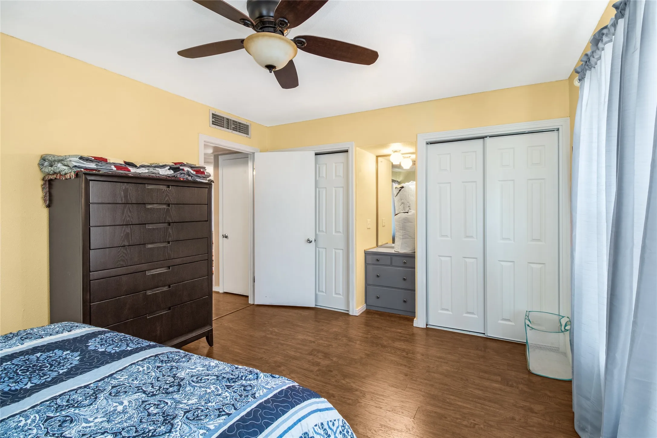 Bedroom featuring ceiling fan, multiple closets, and wood-type flooring