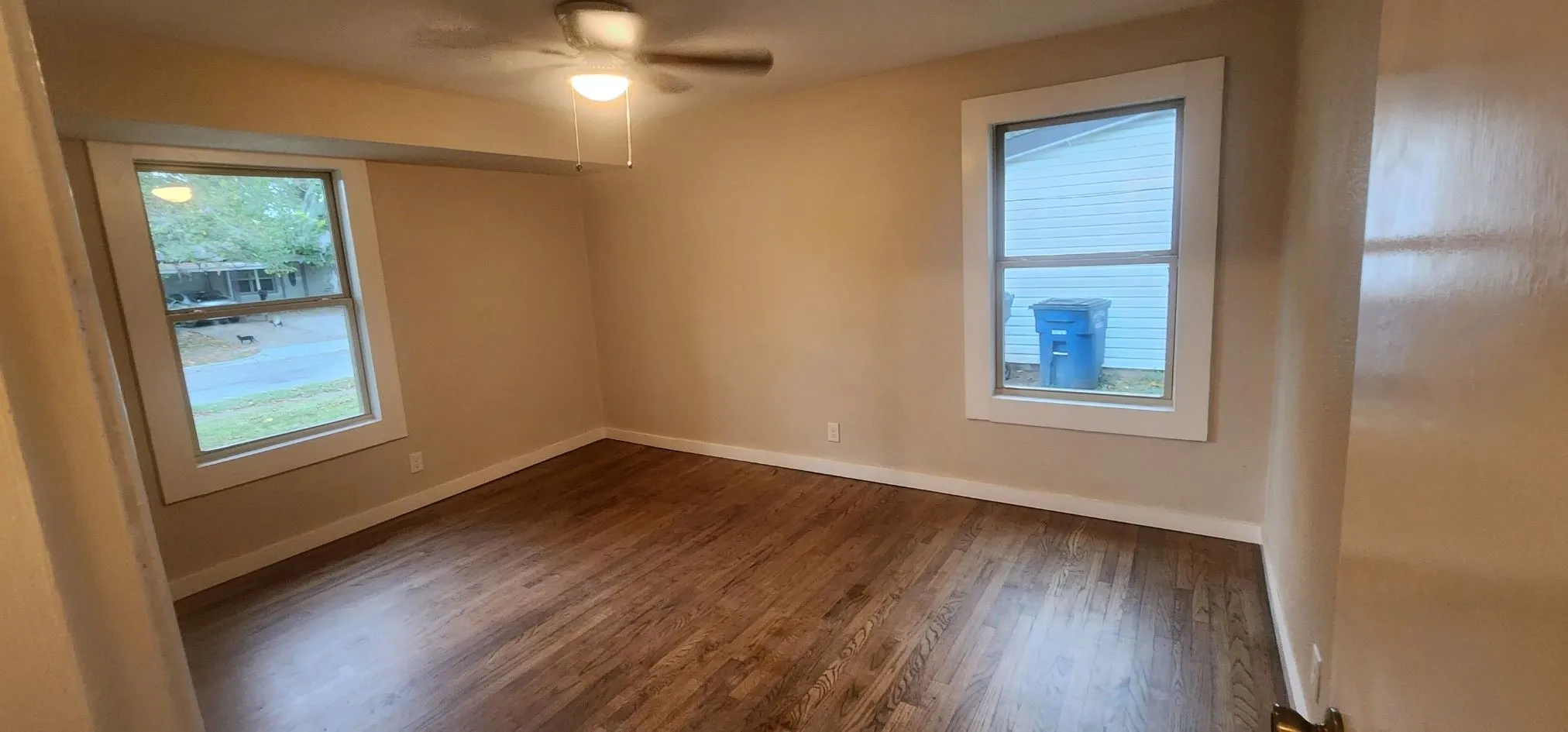 Unfurnished room featuring dark hardwood / wood-style floors, ceiling fan, and a wealth of natural light
