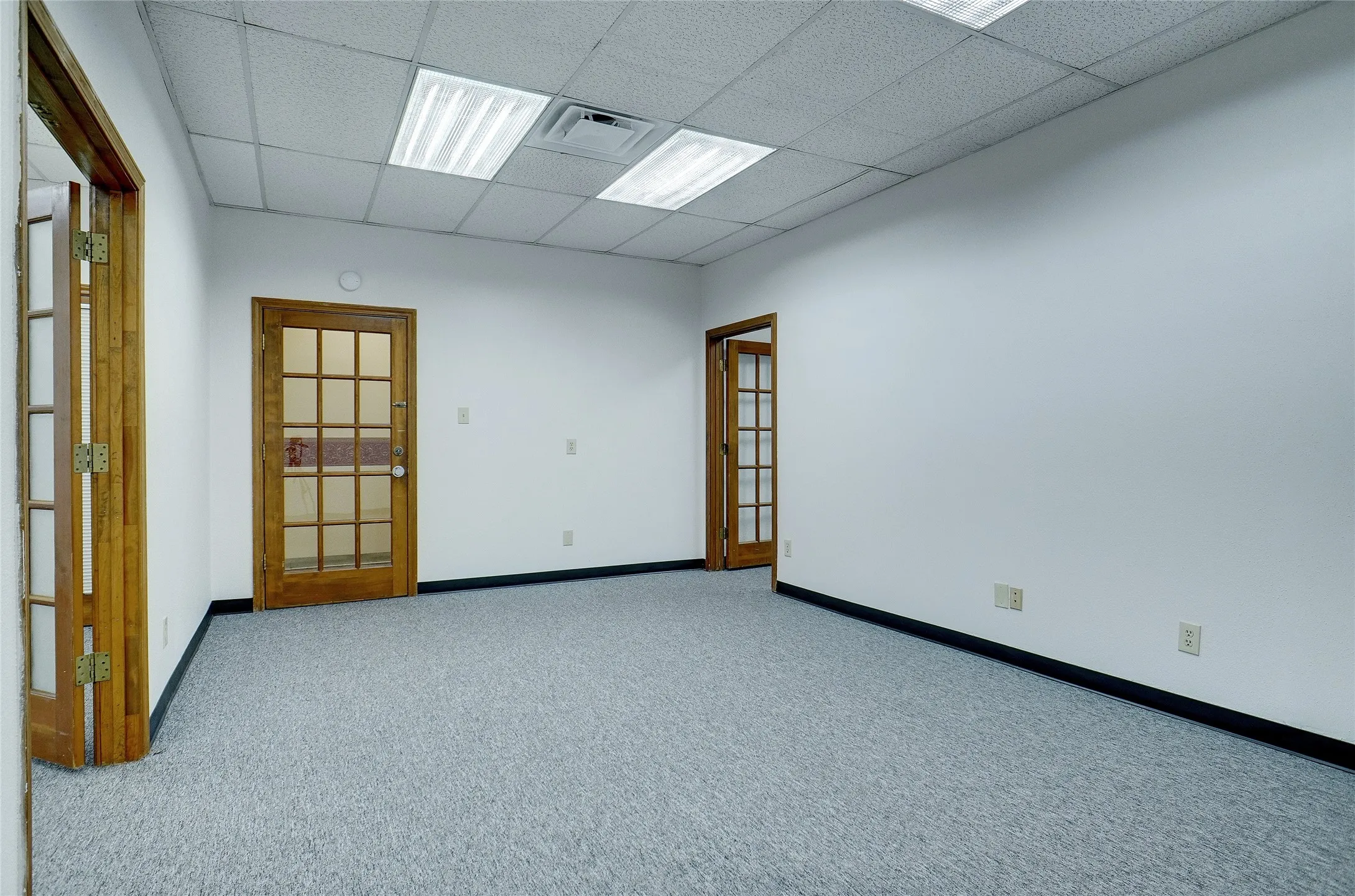 Carpeted office with a paneled ceiling and french doors