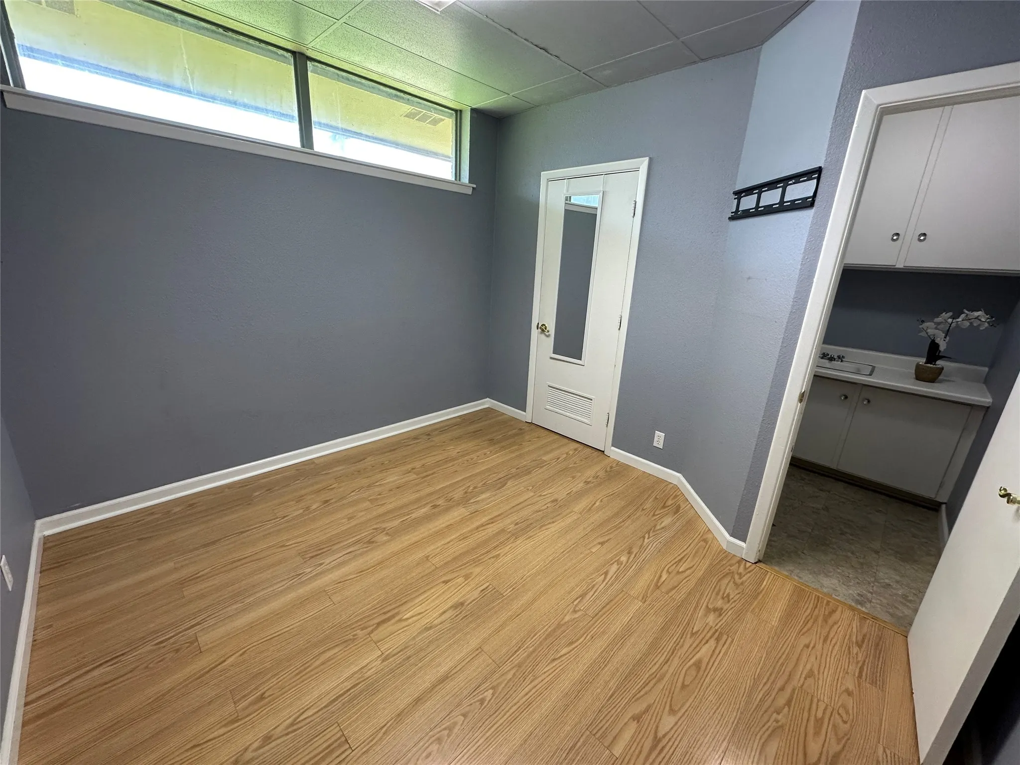 Unfurnished room with light wood-type flooring, storage closet, natural lighting, and private in suite bathroom.