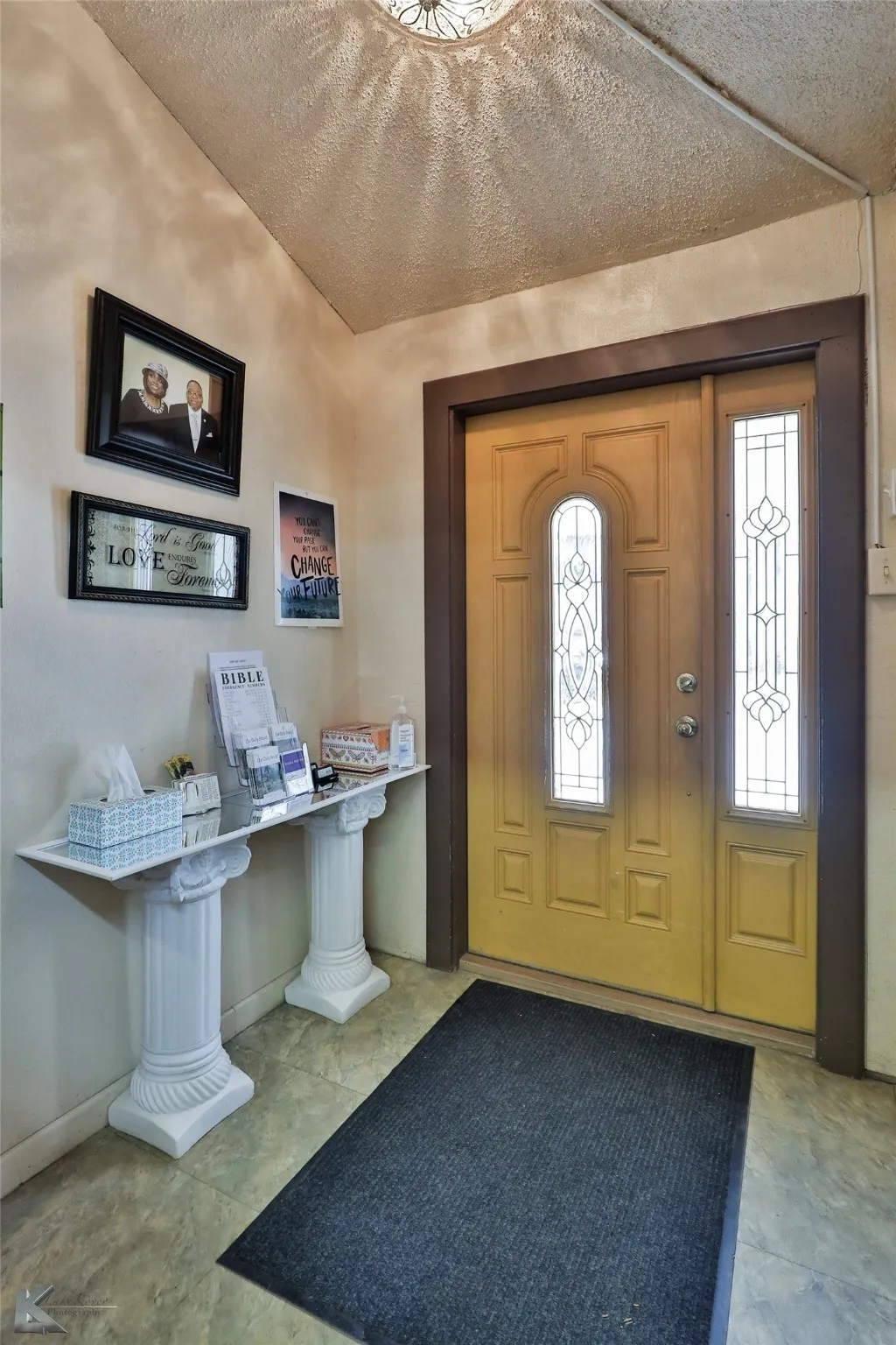 Foyer entrance with a textured ceiling and light tile patterned flooring