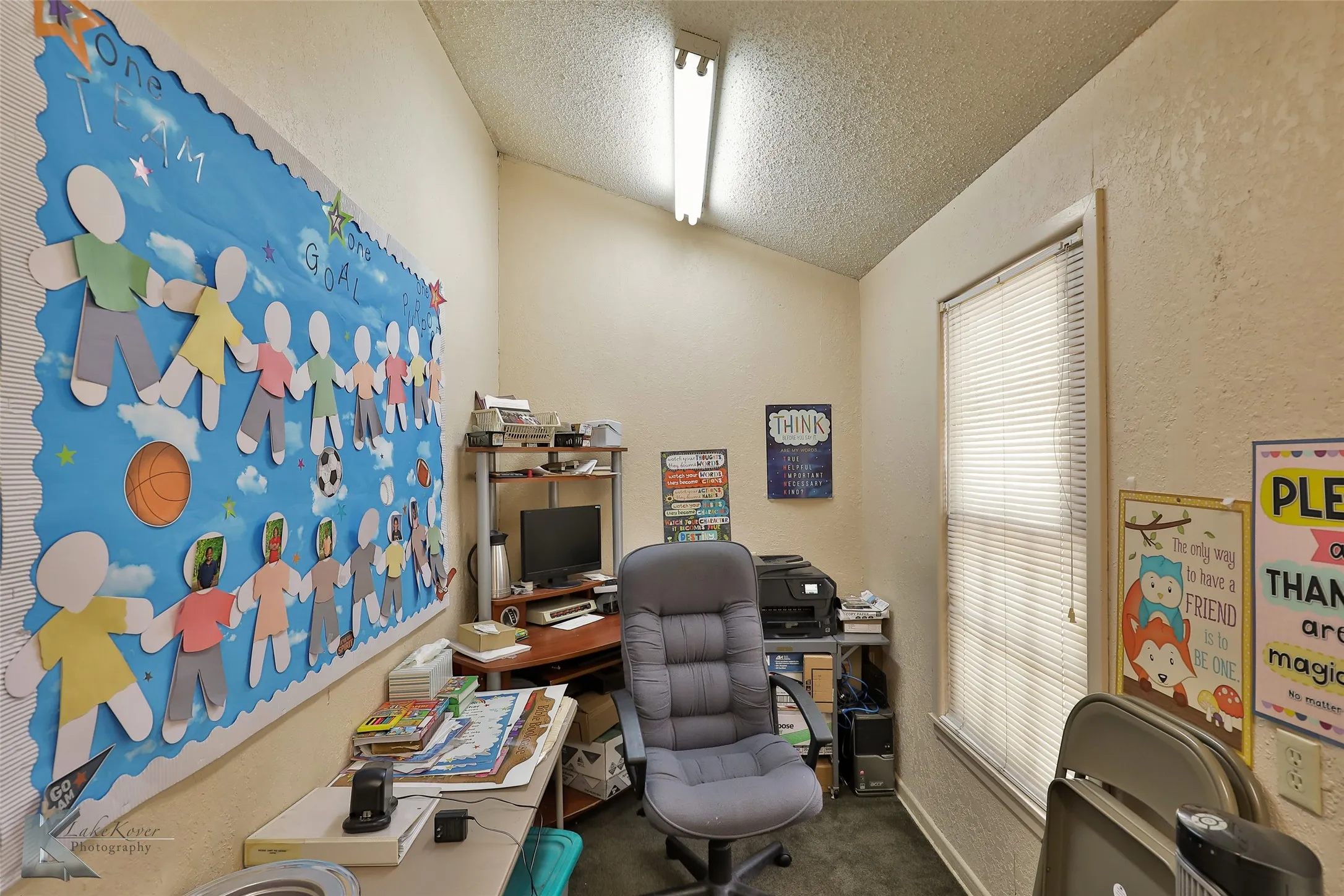 Office area with carpet, vaulted ceiling, and a textured ceiling