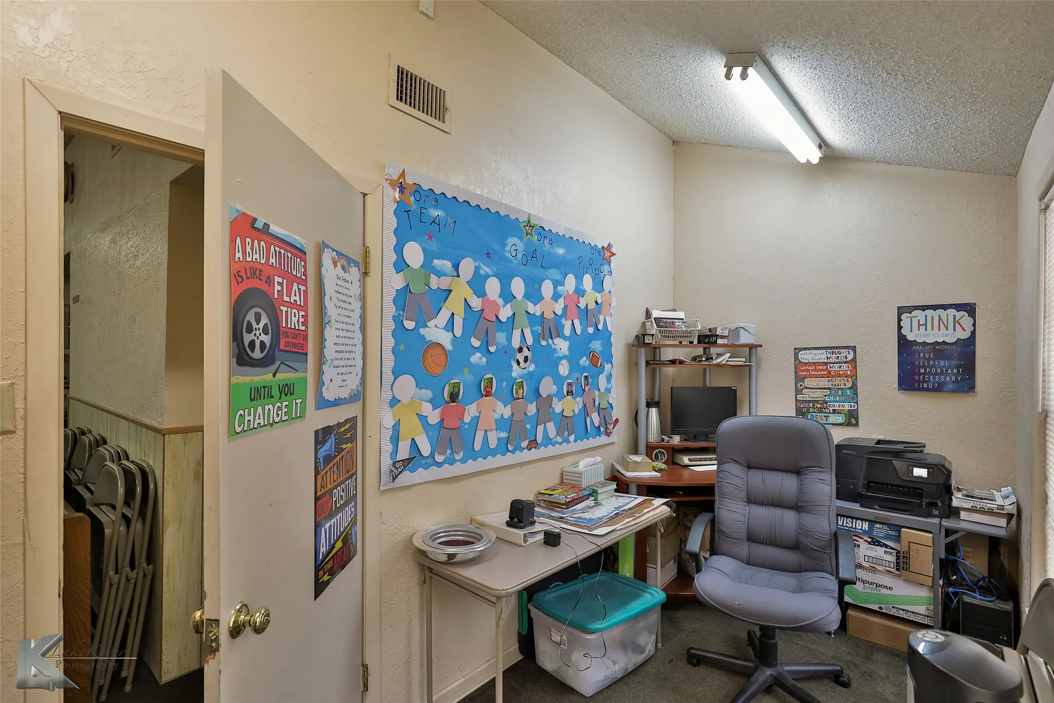 Carpeted office with a textured ceiling and vaulted ceiling